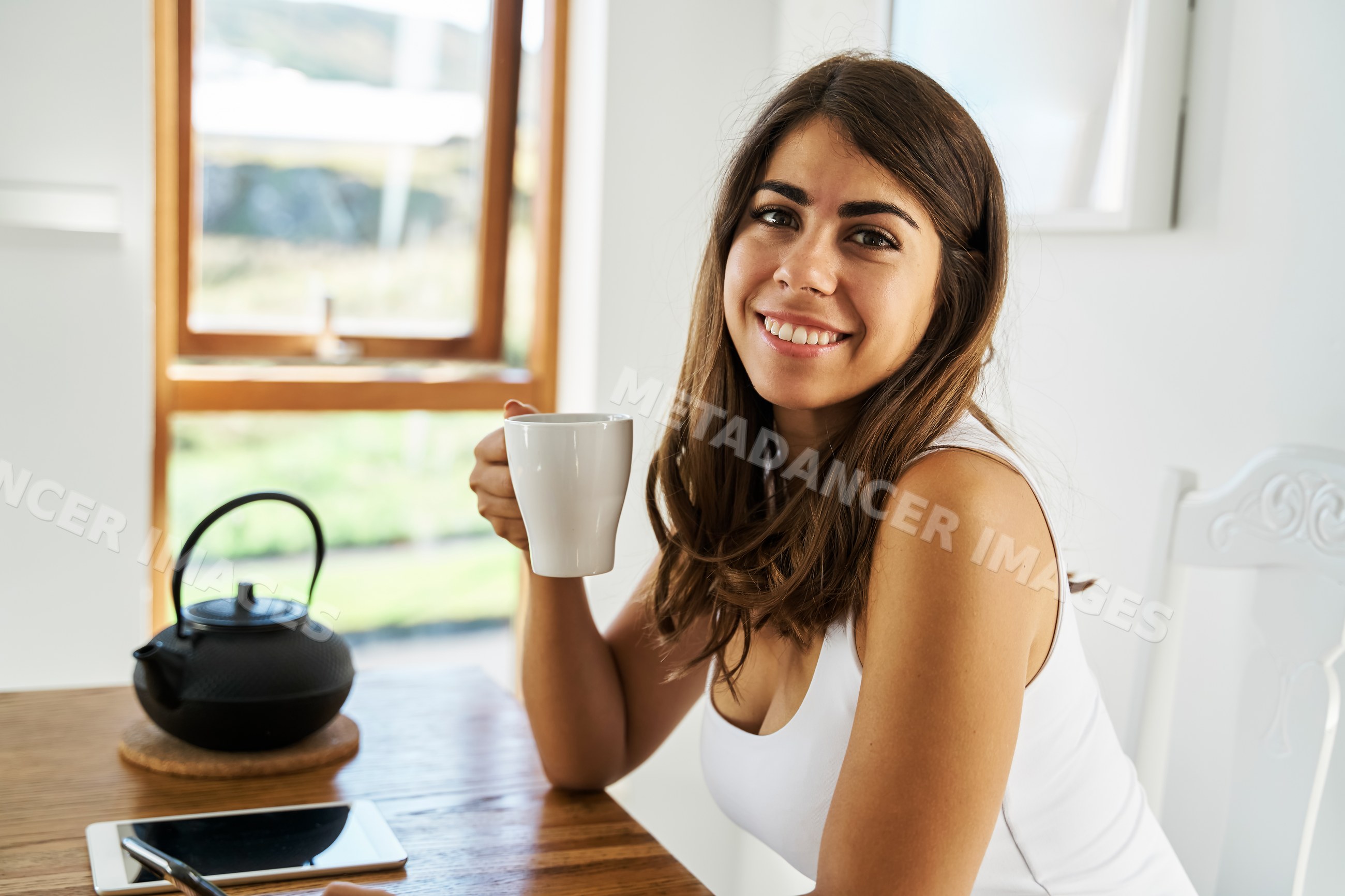 A young white woman enjoying tea in a bright indoor setting