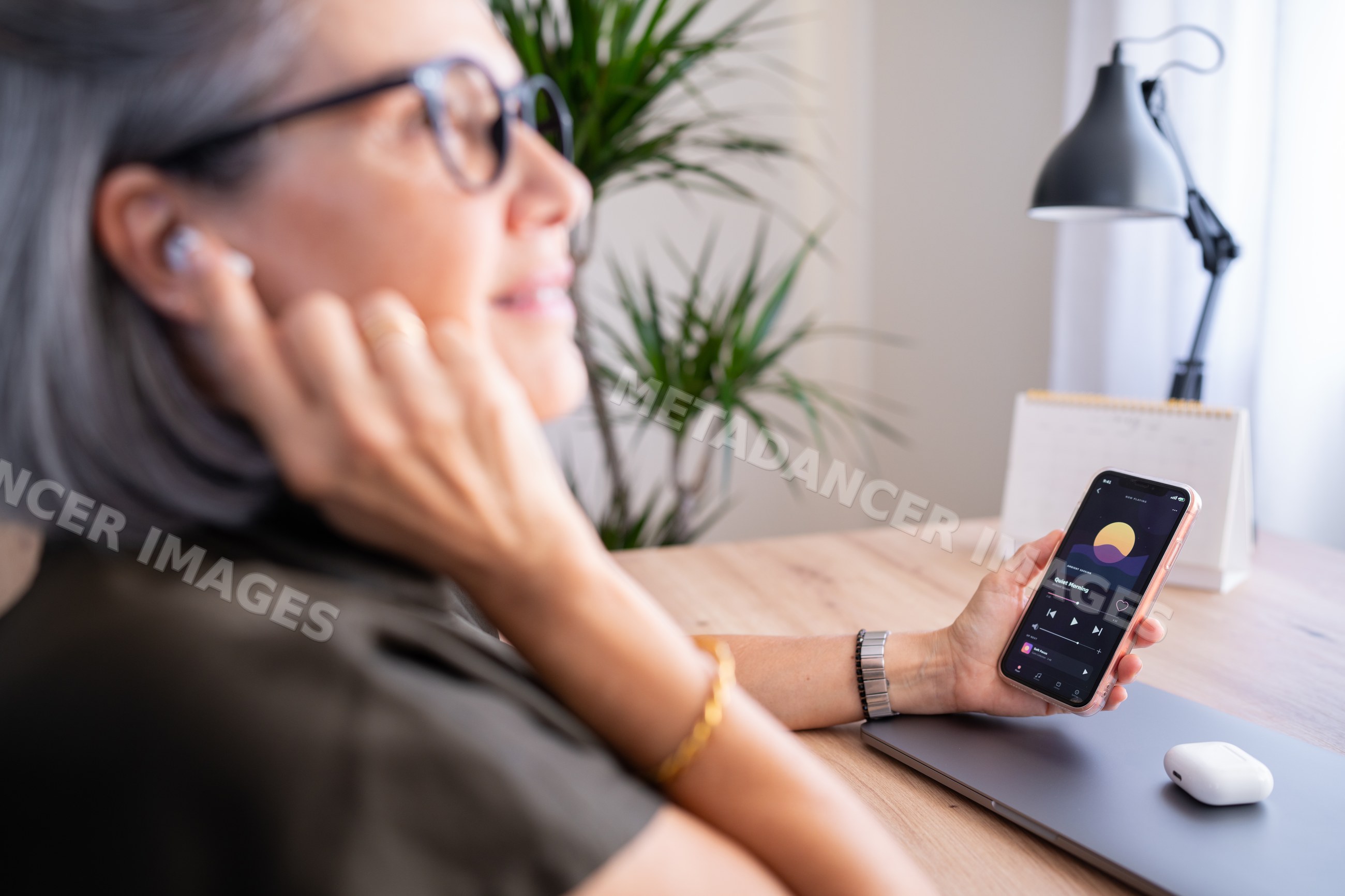 White woman listening to music on wireless earbuds holding smartphone