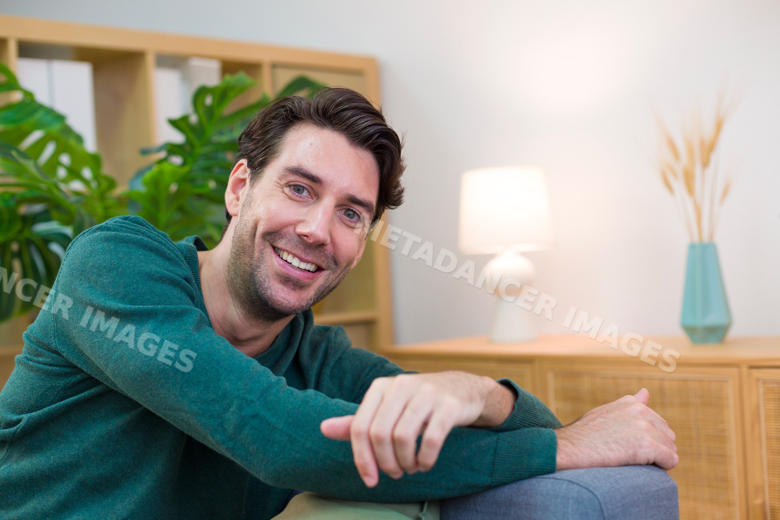 White man smiling and relaxing in a cozy living room setting