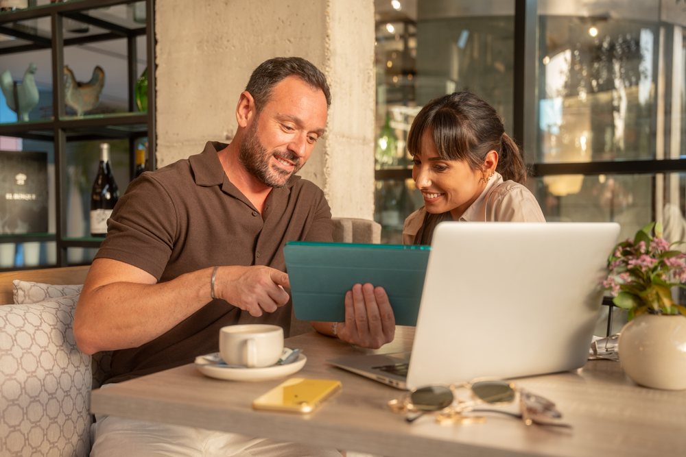 Coworkers collaborating on tablet and laptop in Seville cafe