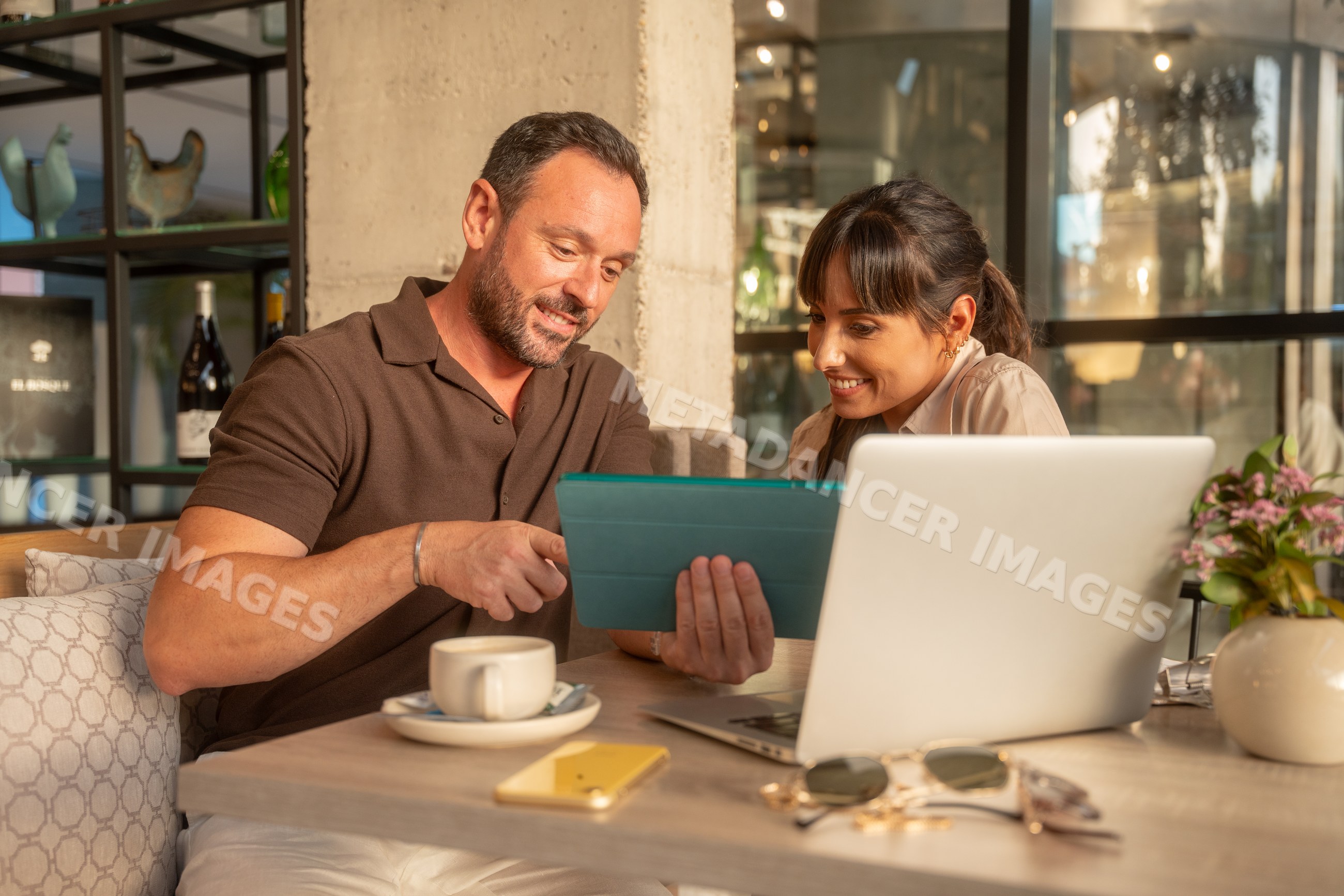 Coworkers collaborating on tablet and laptop in Seville cafe