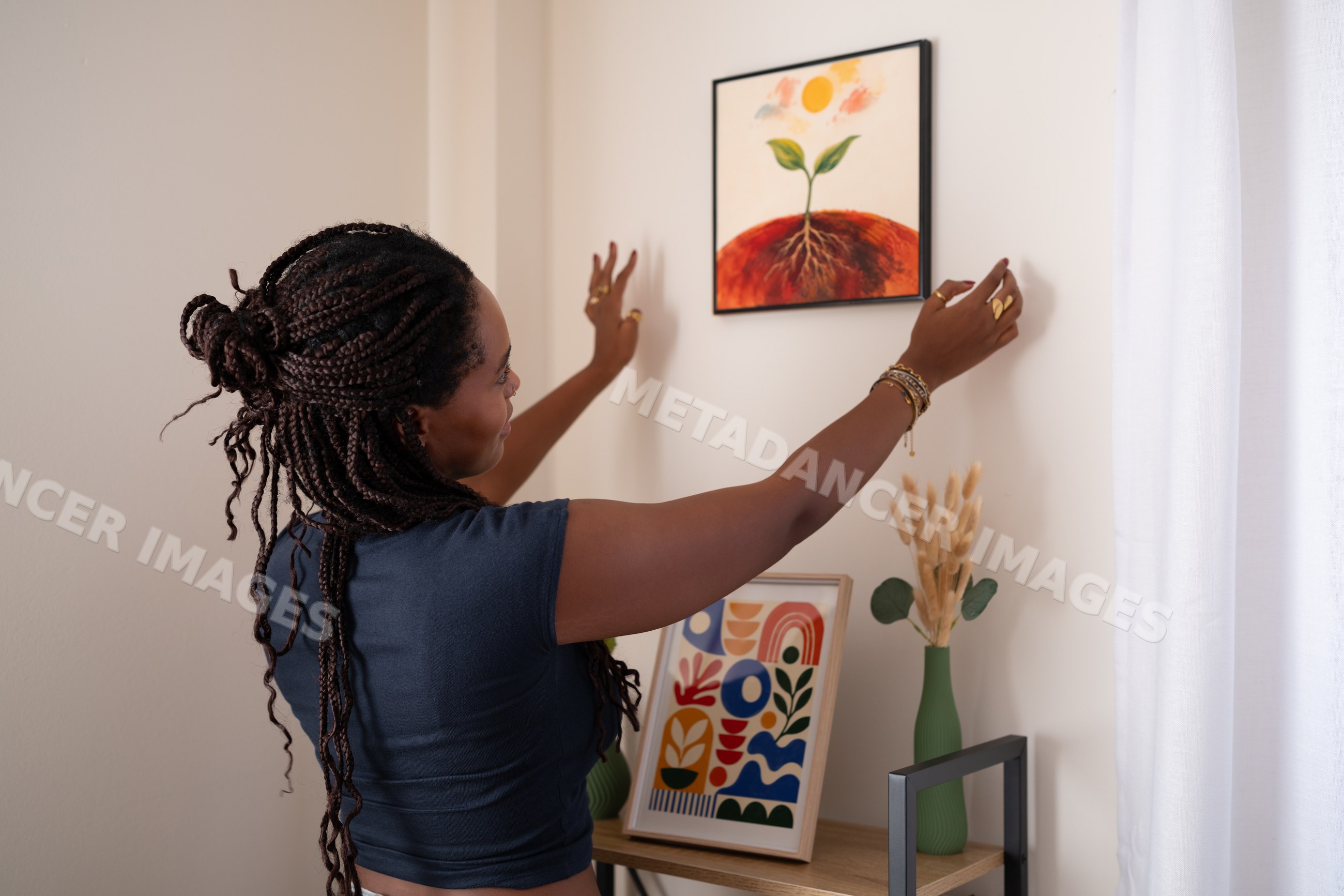 African American woman hanging a painting on the wall