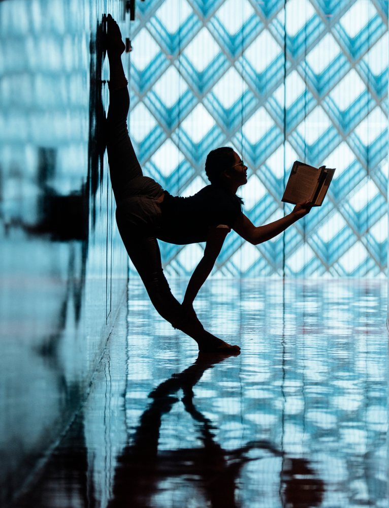 A woman stretches and reads a book