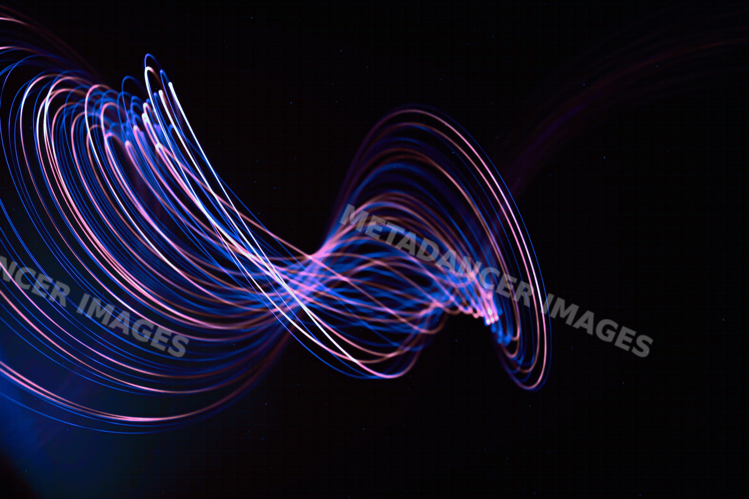 Abstract light trails create dynamic wave patterns on a dark
