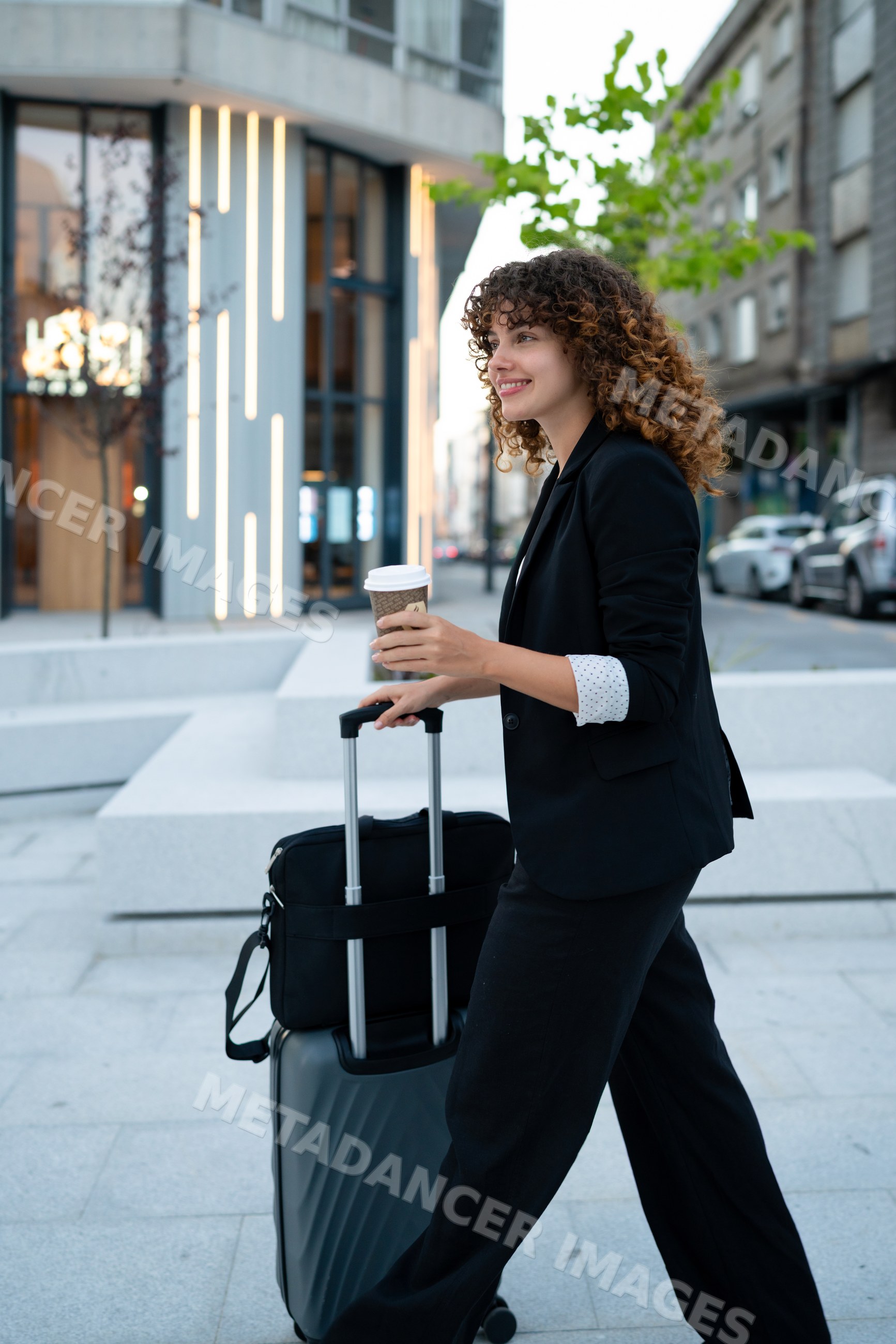 Business white woman walking with luggage and coffee on urban street