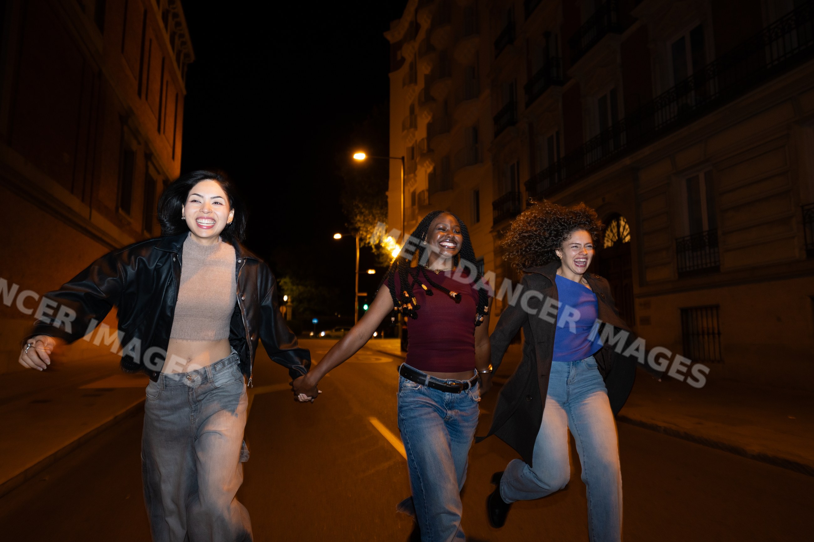 Hispanic, white and Black women running joyfully together on a city