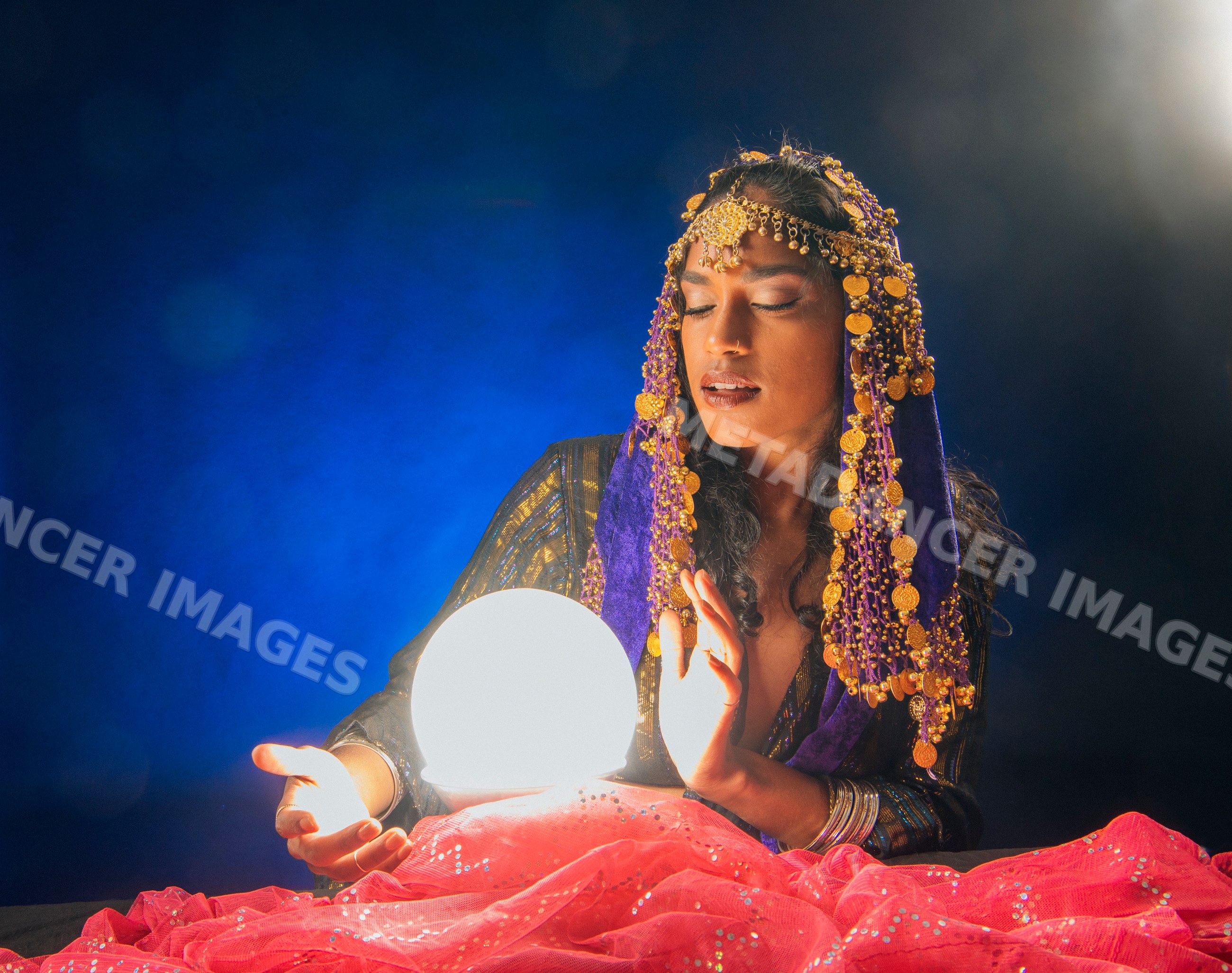 A South Asian woman acts as a fortune teller with a glowing crystal