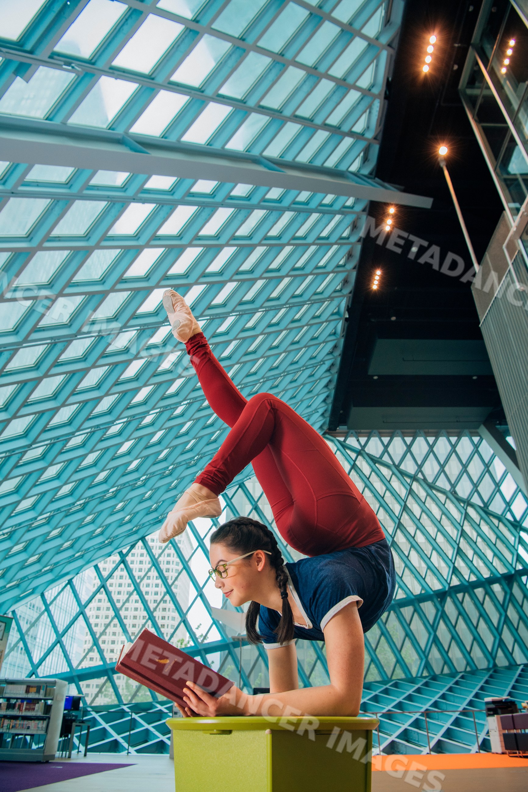 A woman balances in an acrobatic pose while reading inside the Seattle