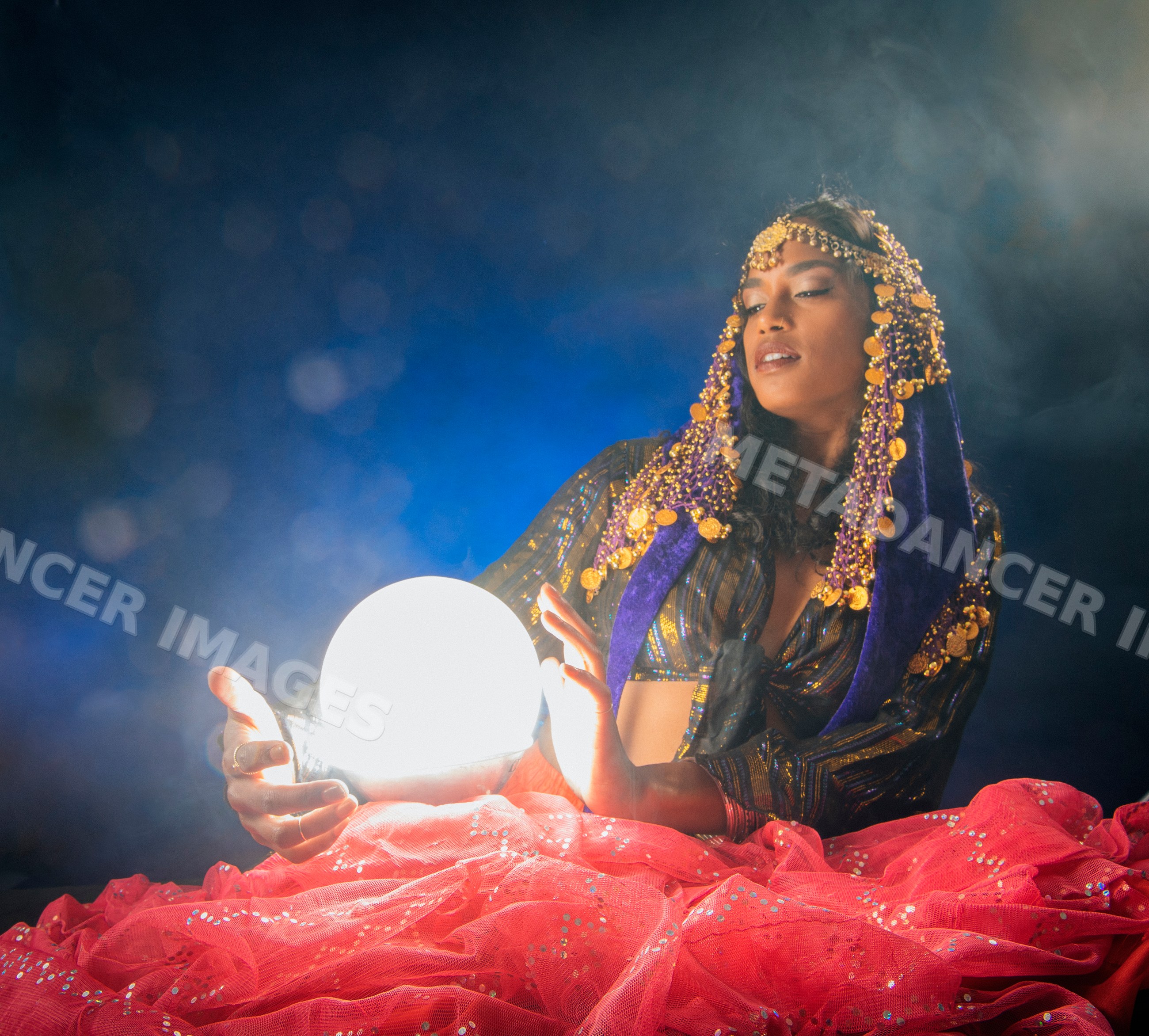 A South Asian woman dressed as a fortune teller holding a glowing
