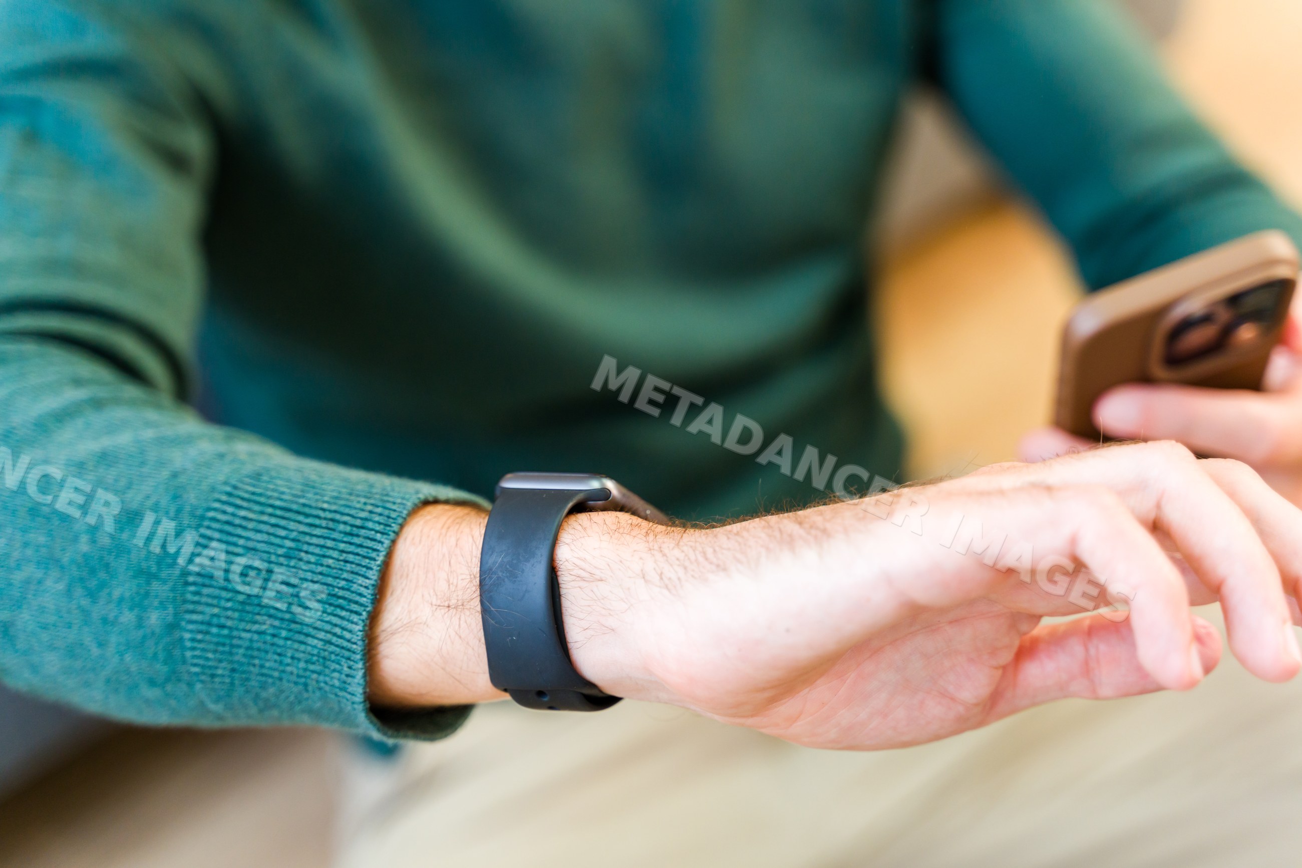 White man wearing smartwatch using smartphone indoors