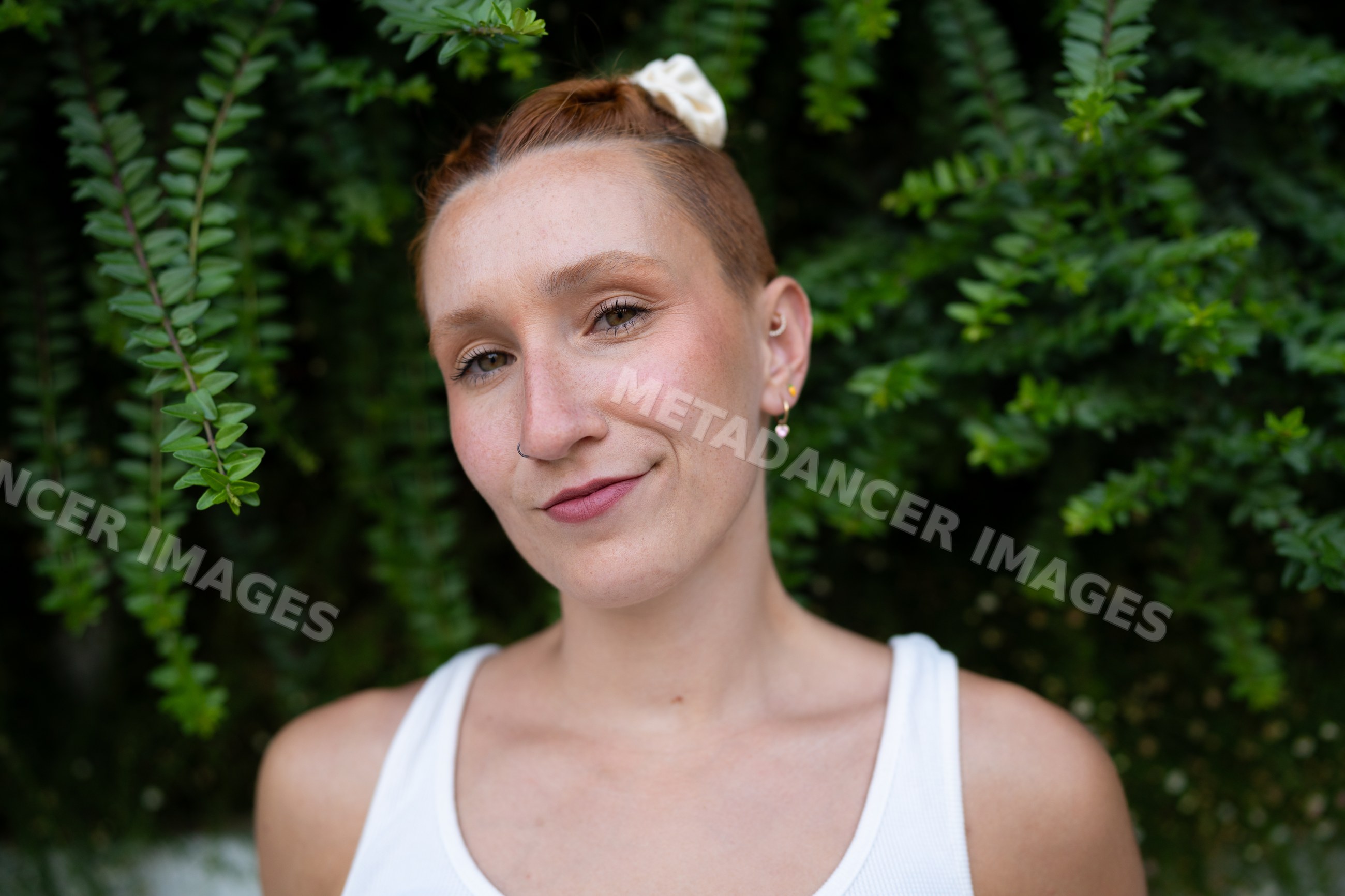 A confident young white woman smiles outdoors