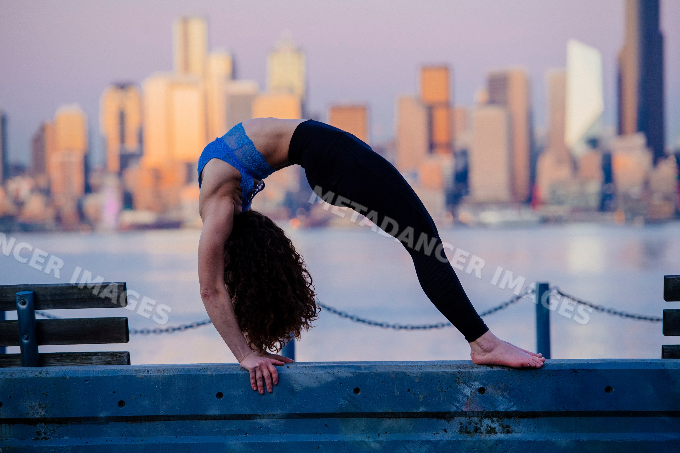 White woman practicing backbend yoga pose by Seattle waterfront