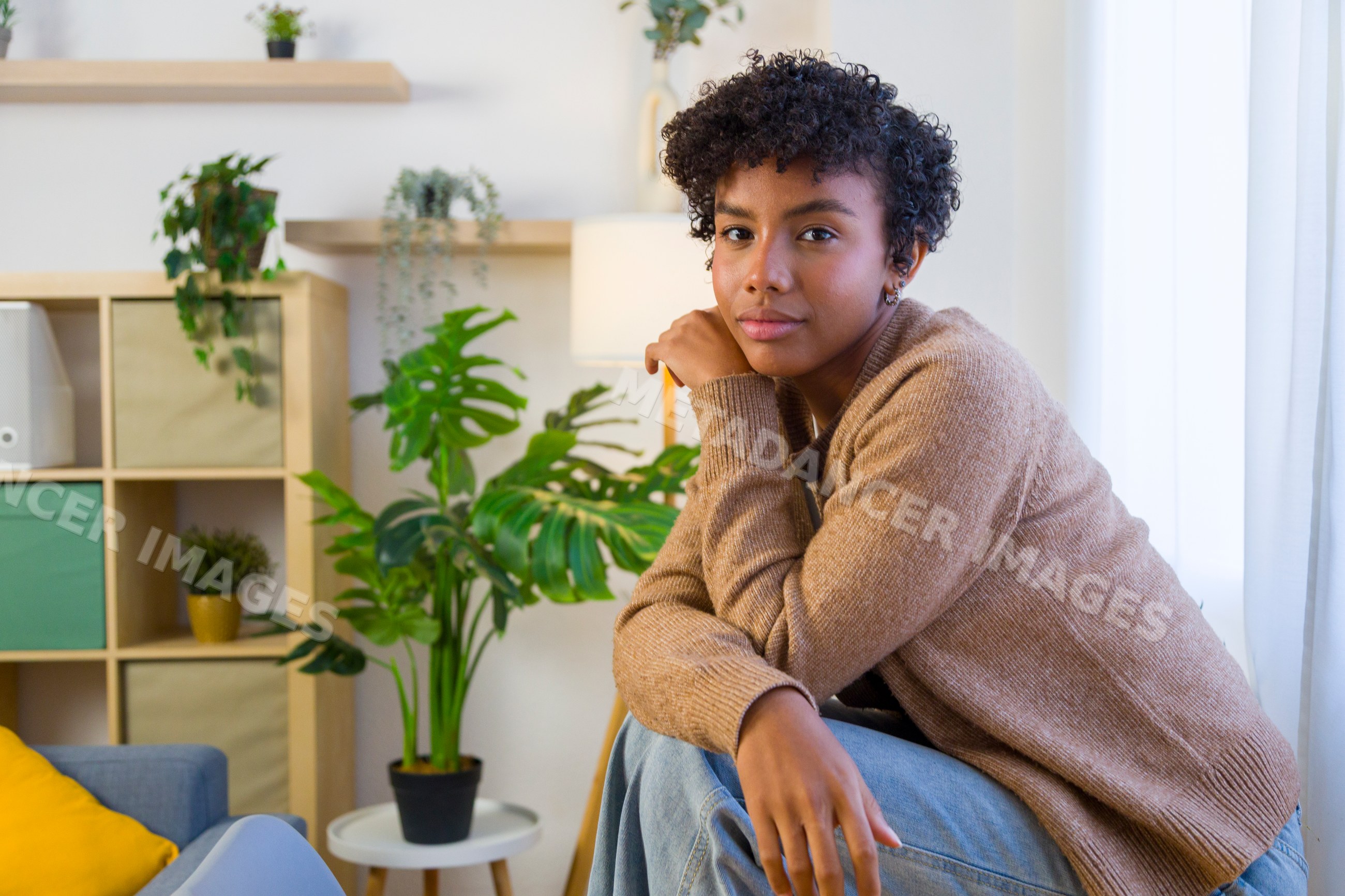 Young African American woman sitting indoors with plants and modern