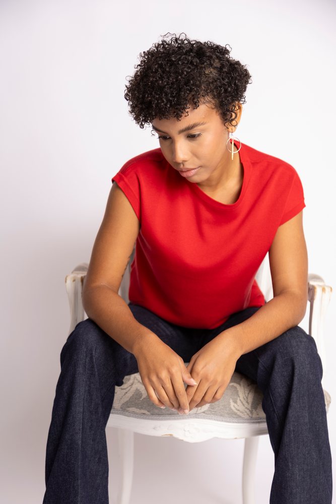 Hispanic woman with curly hair sitting on white chair