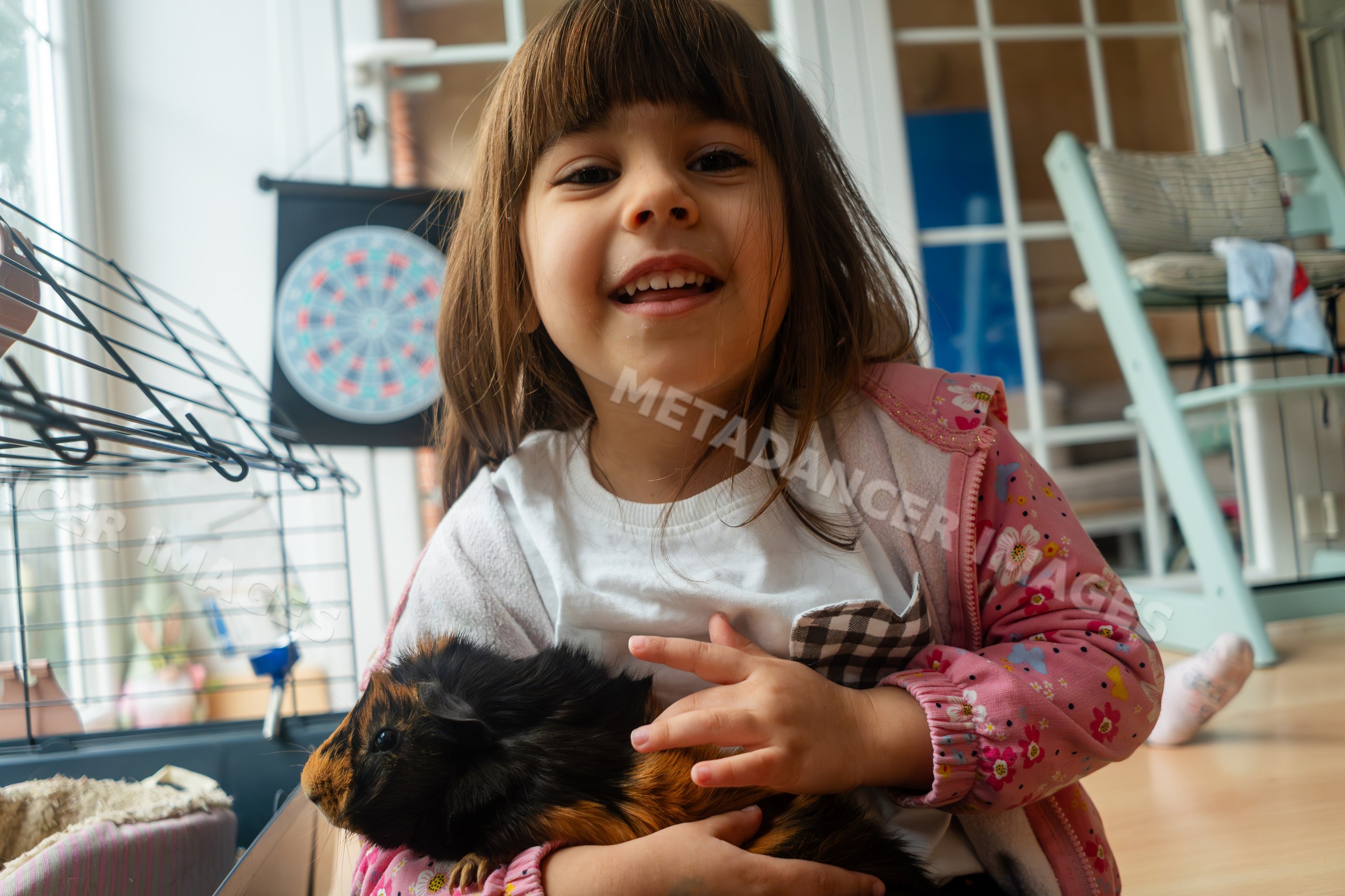 A smiling white girl holding a guinea pig inside a home in Madrid