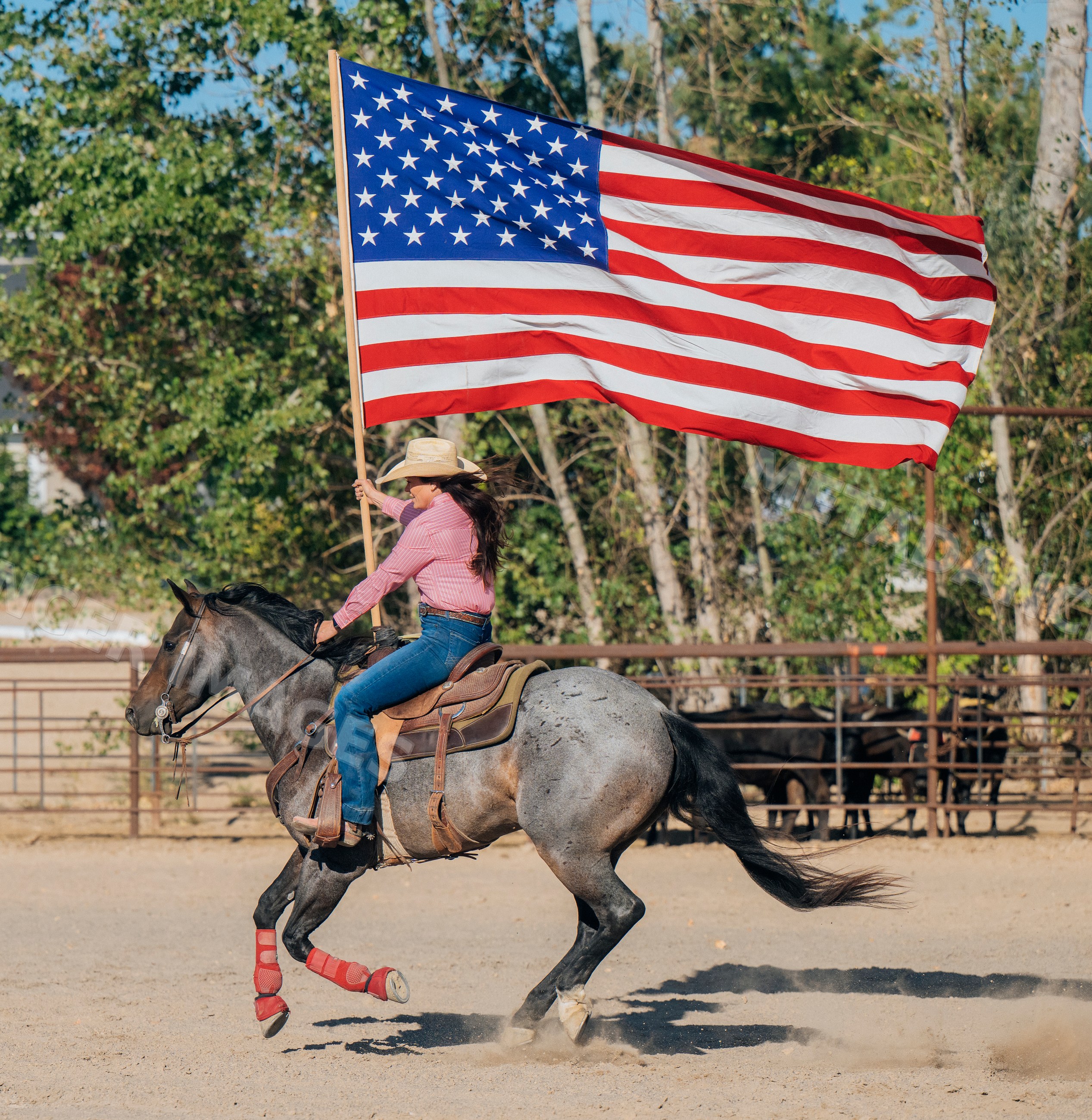 White woman riding horse holding american flag at Southwest USA ranch