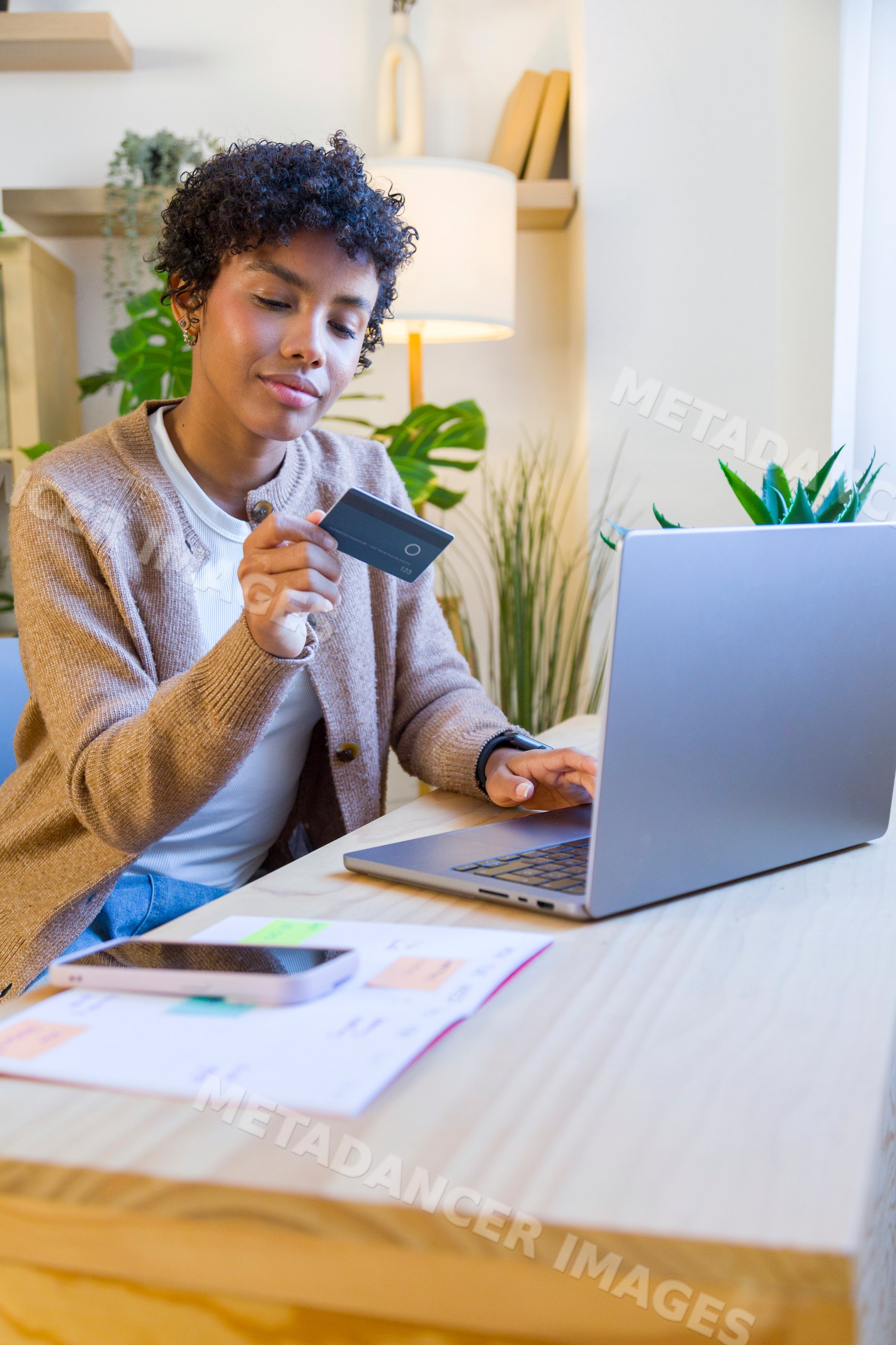 African American woman holding credit card using laptop in home office
