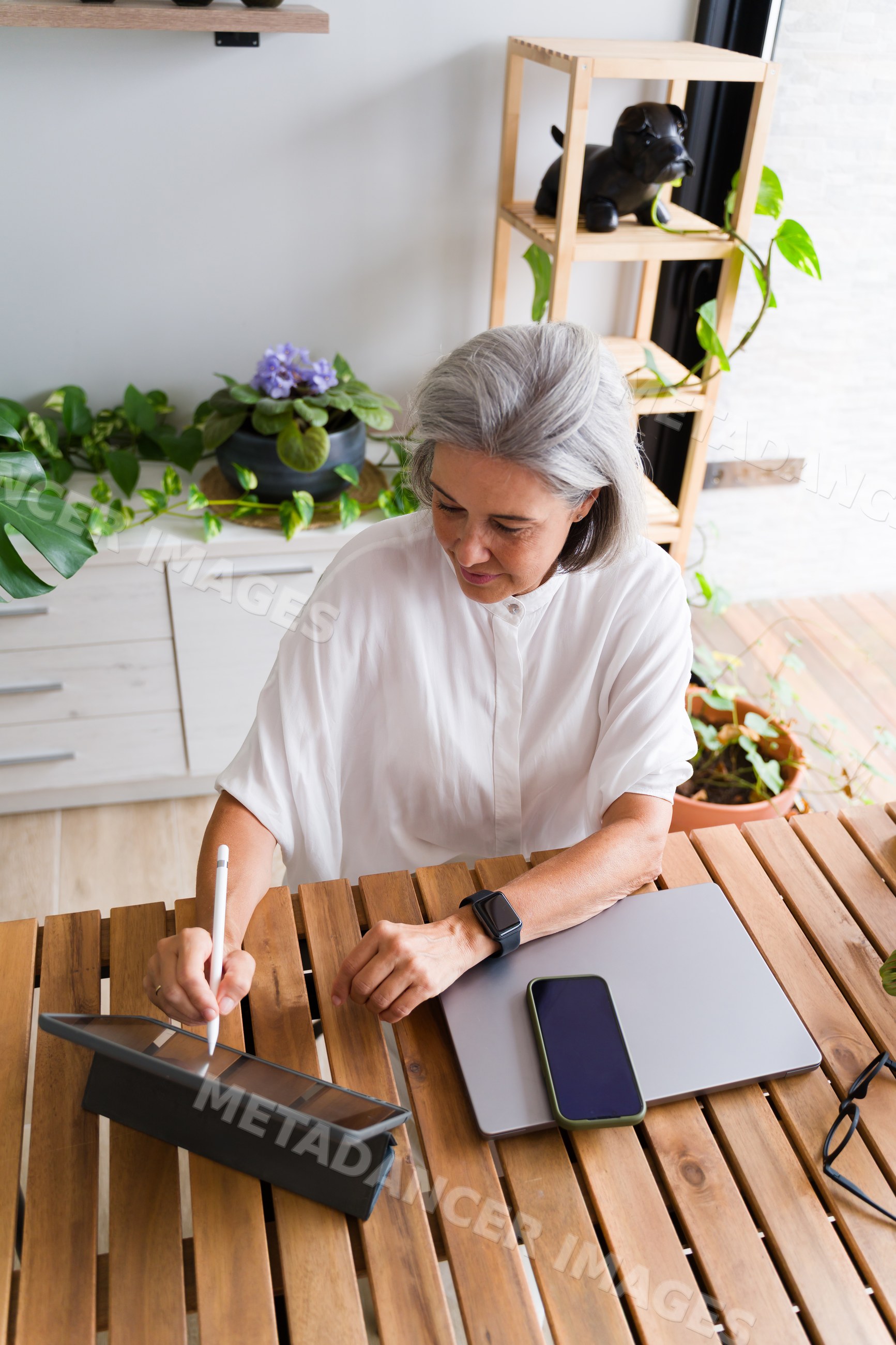 White Woman using digital pen on tablet at wooden table in home office