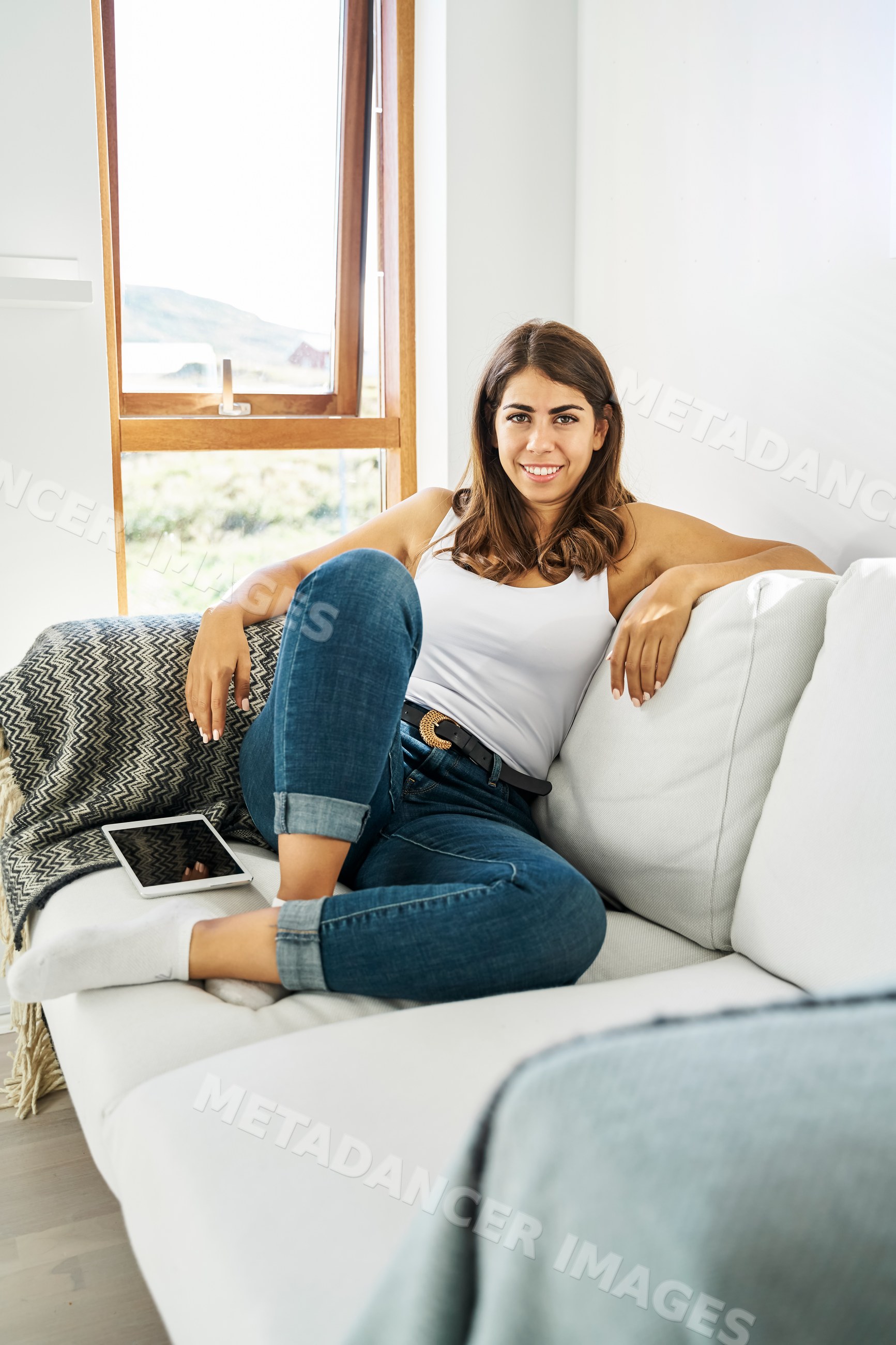 A woman relaxing on a white sofa in a bright living room