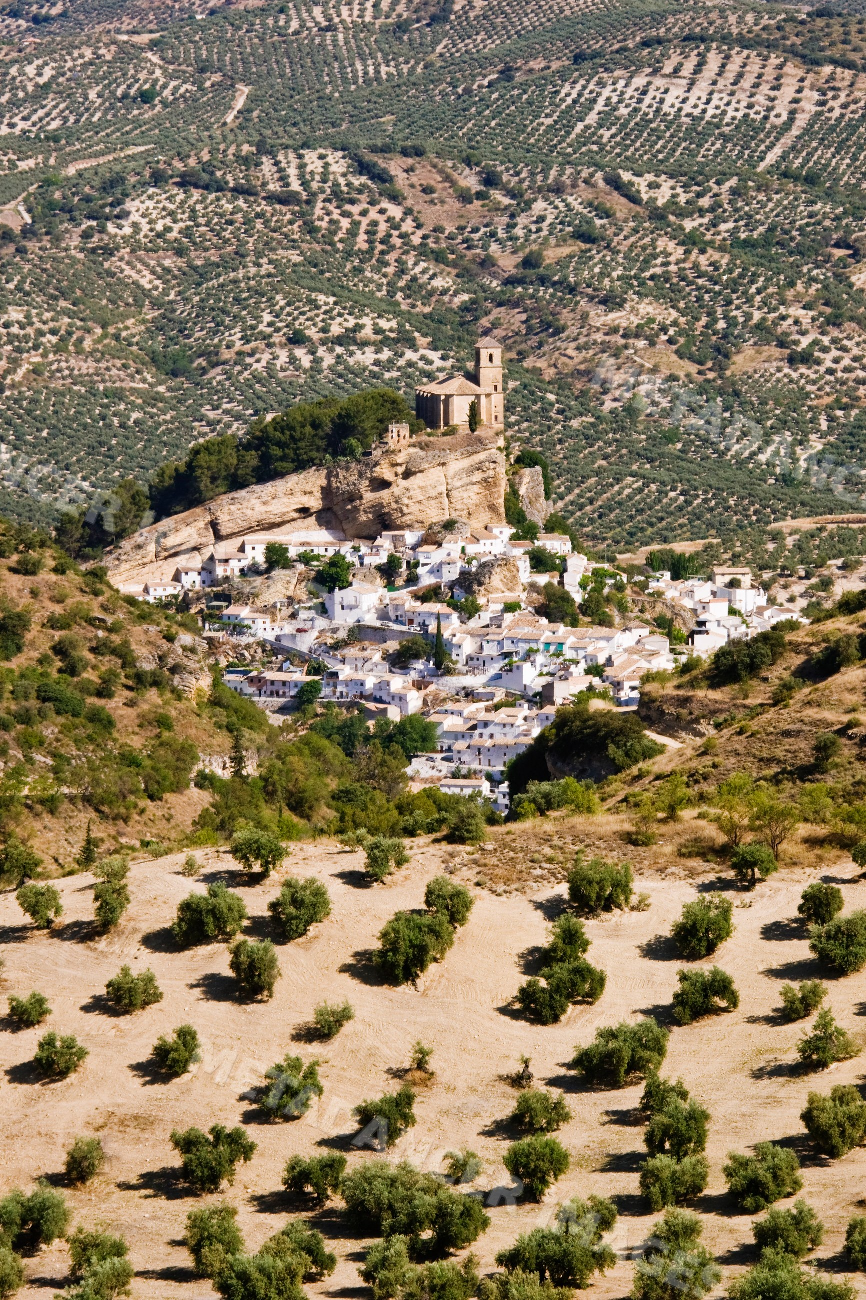 Montefrio village with church on rocky hill and olive groves, Spain