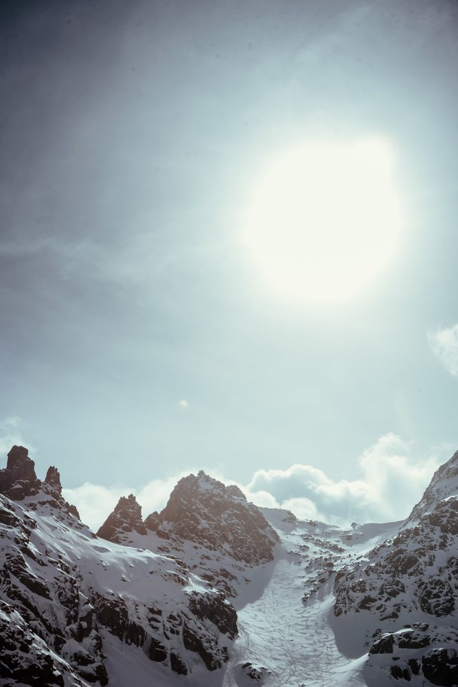 Snowy mountain peaks with bright sun and rocky terrain