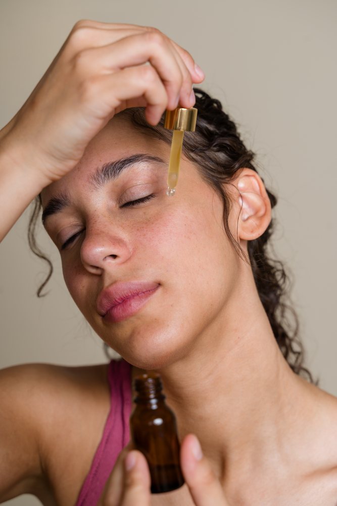 Hispanic woman applying face serum for skin care during beauty shoot