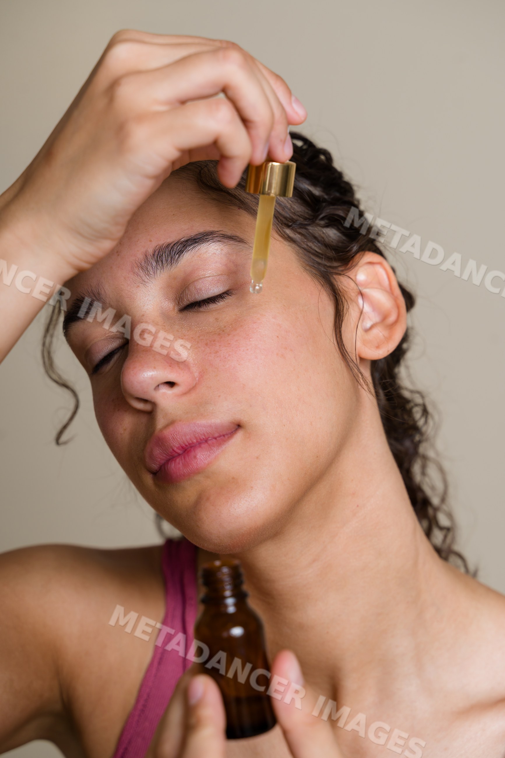 Hispanic woman applying face serum for skin care during beauty shoot