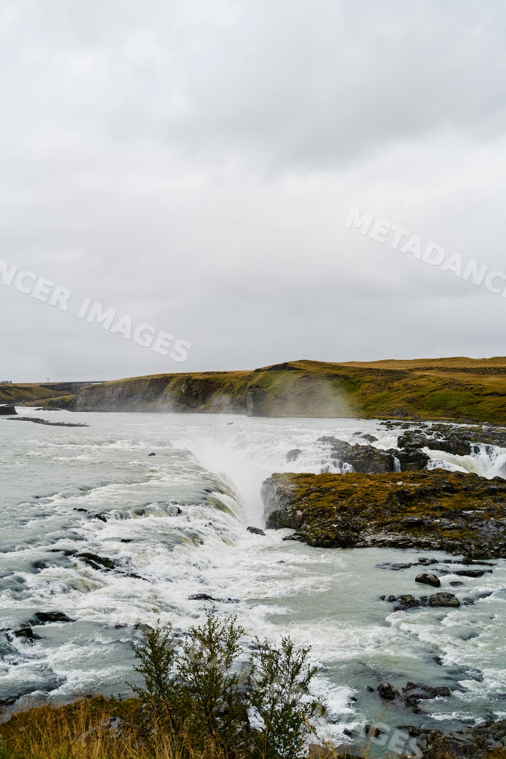 Waterfall flowing over rocky cliffs into a river