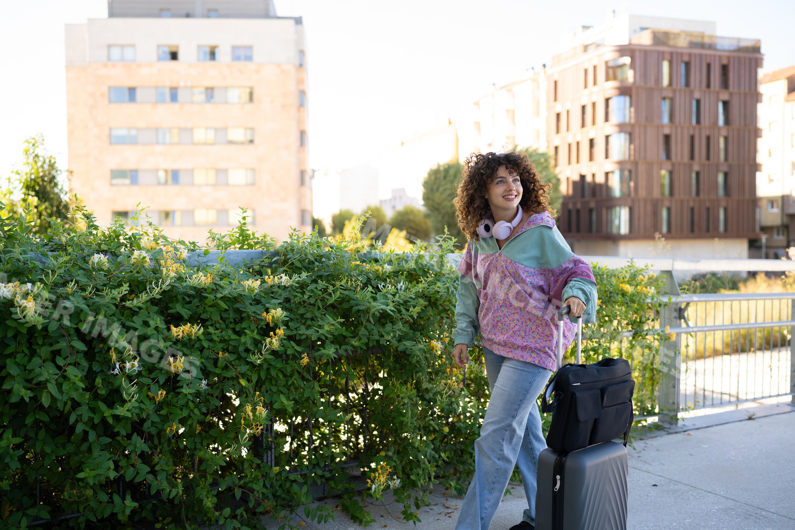 White woman walking with luggage along an urban sidewalk