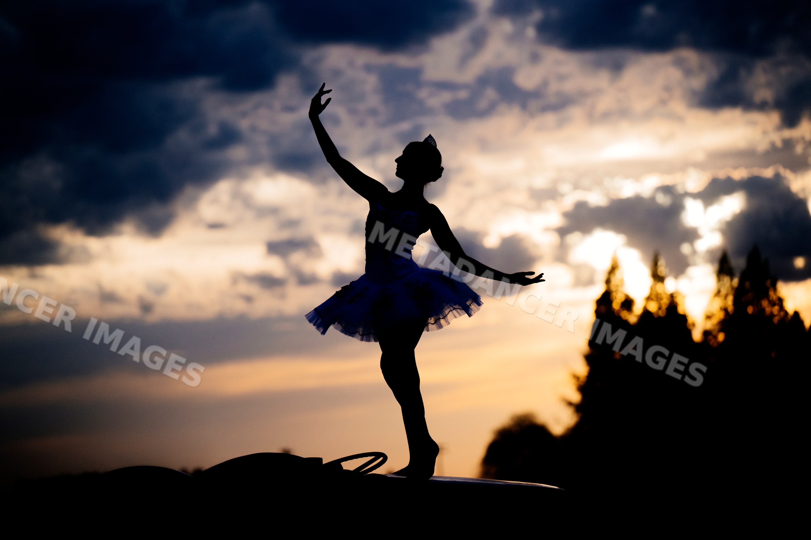 Ballet white dancer silhouette posing gracefully outdoors at sunset