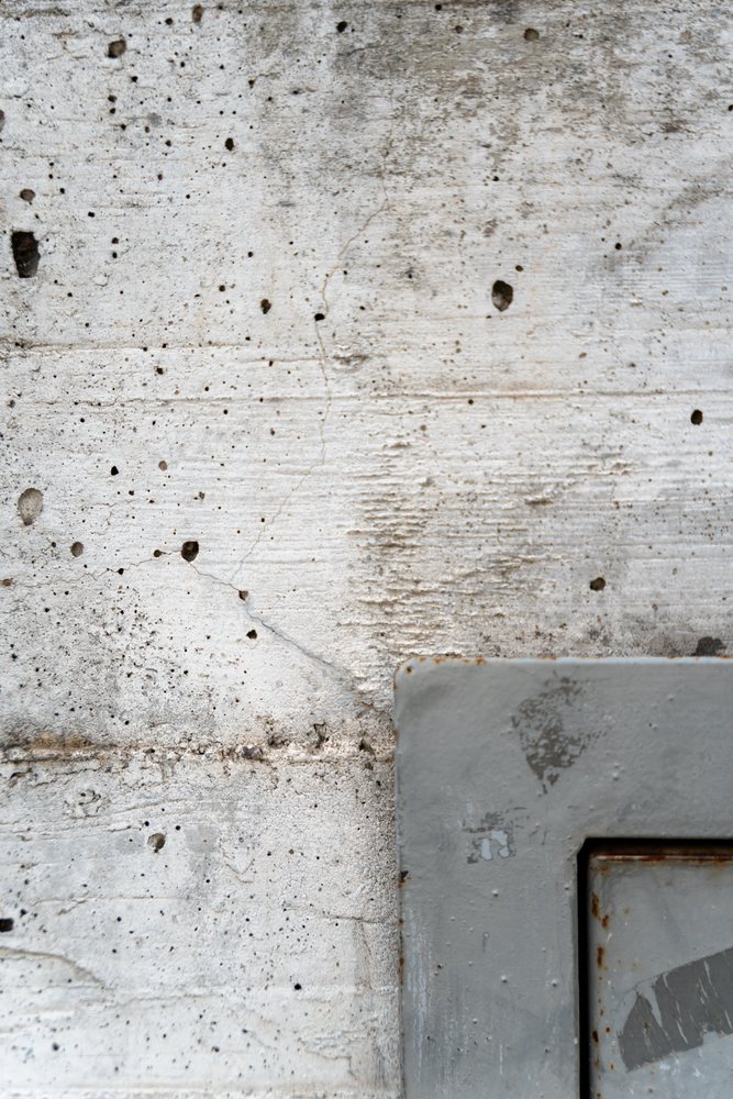 Weathered concrete wall texture with rusted metal plate corner