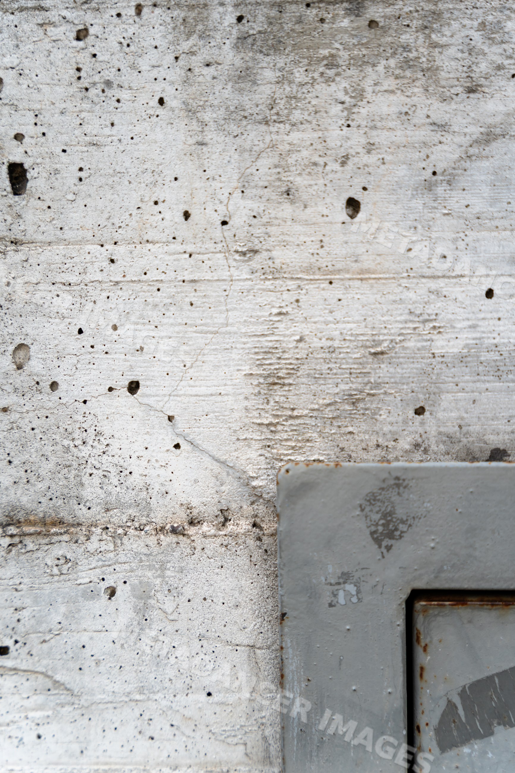 Weathered concrete wall texture with rusted metal plate corner
