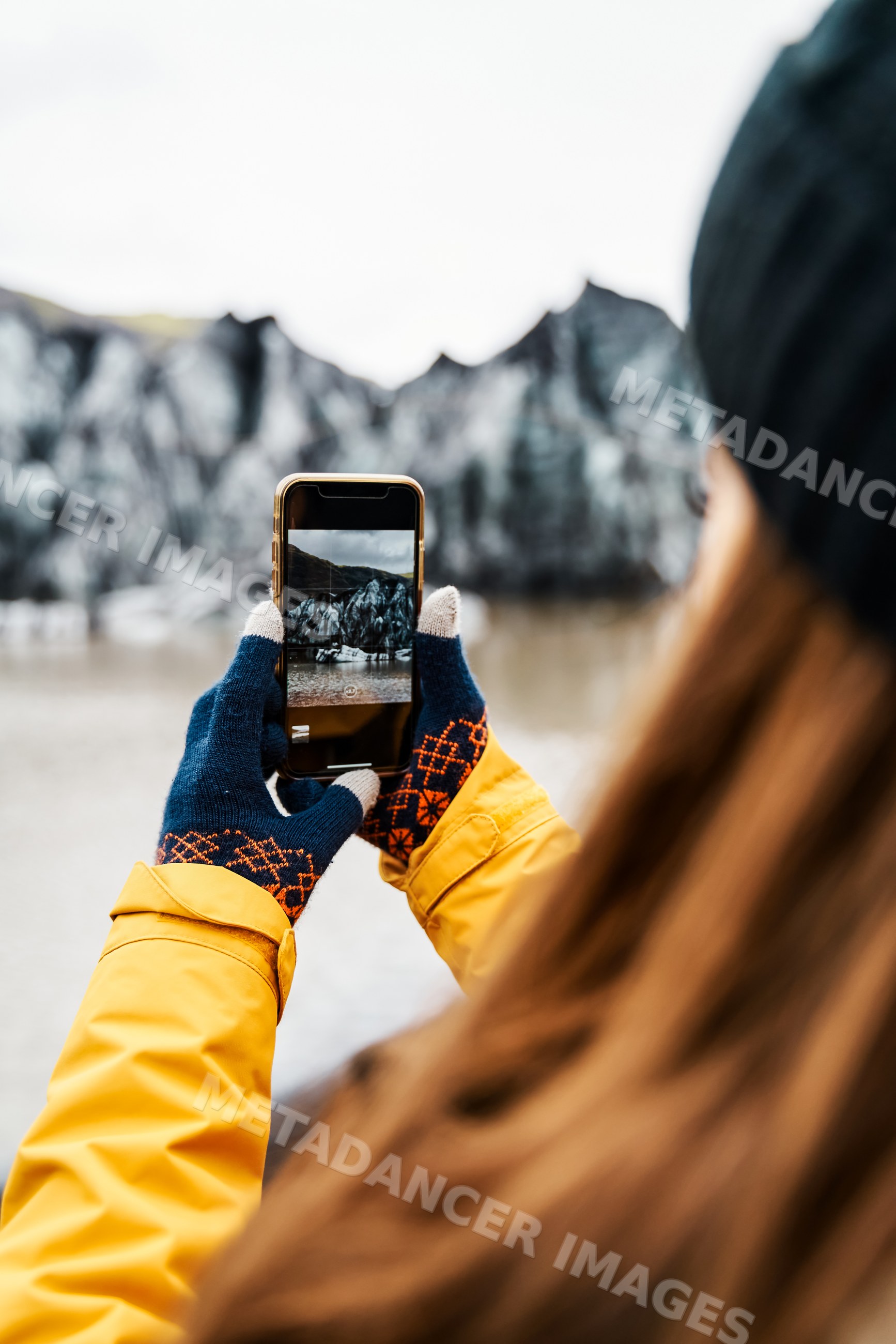A white person takes a photo of rocky shoreline scenery