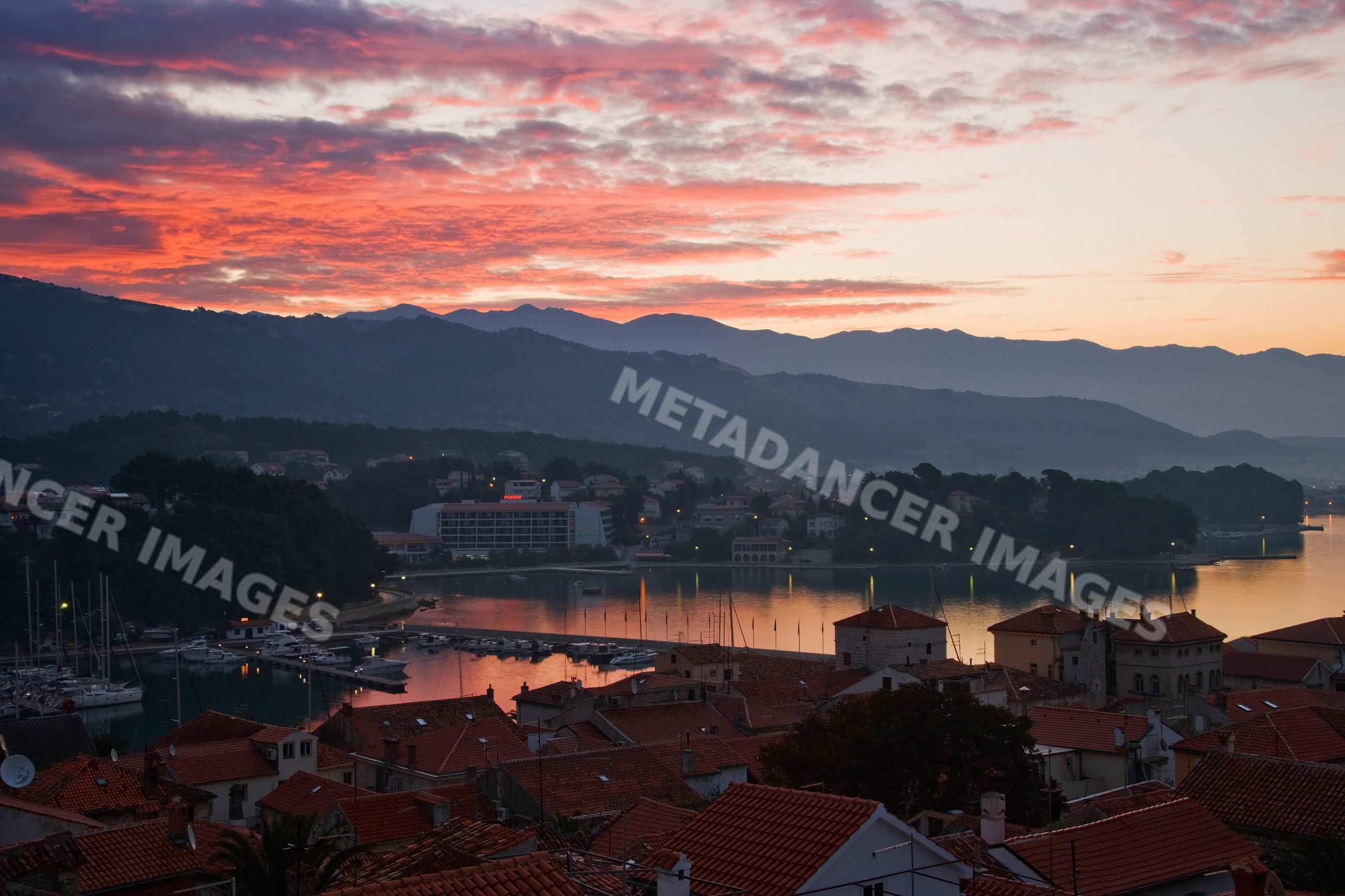 Town of rab harbor at dawn with boats and mountains on rab island