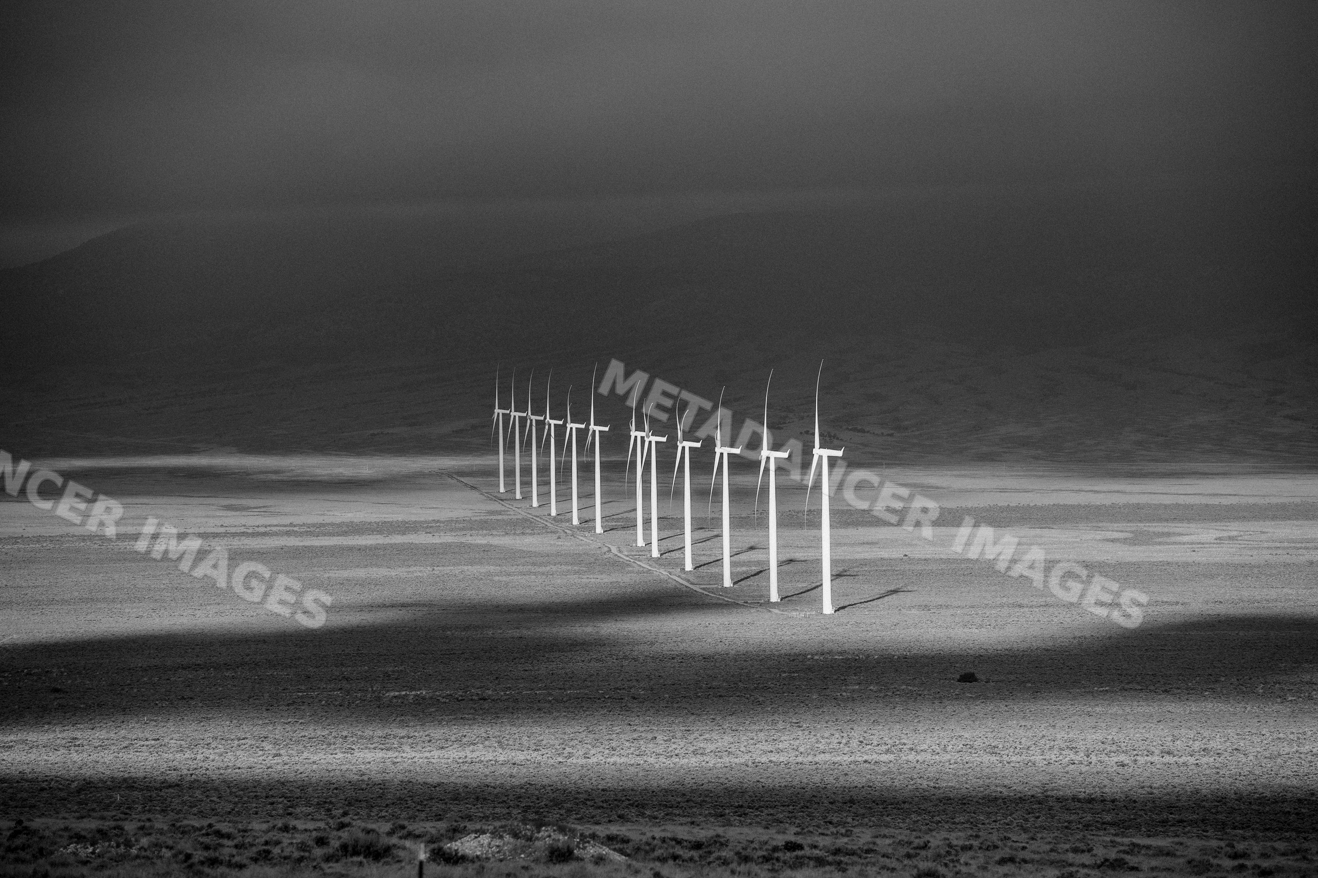 Line of wind turbines in desert landscape with mountains