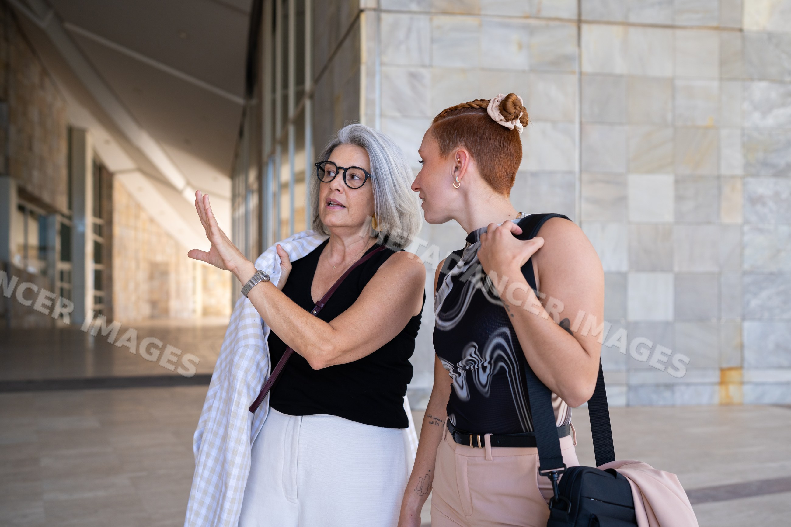 Two businesswomen conversing in a modern marble hallway