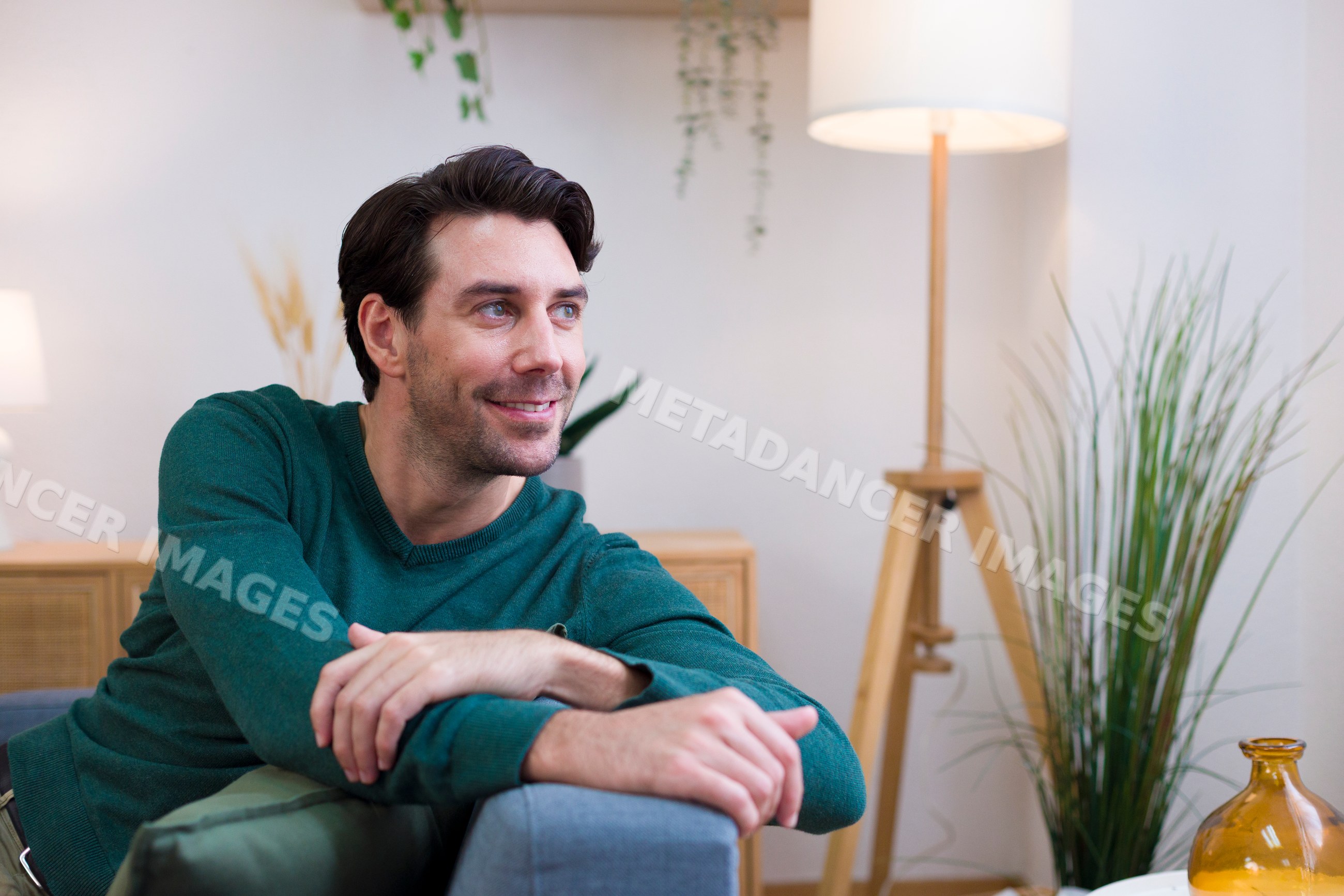 White man smiling on a couch in a cozy living room