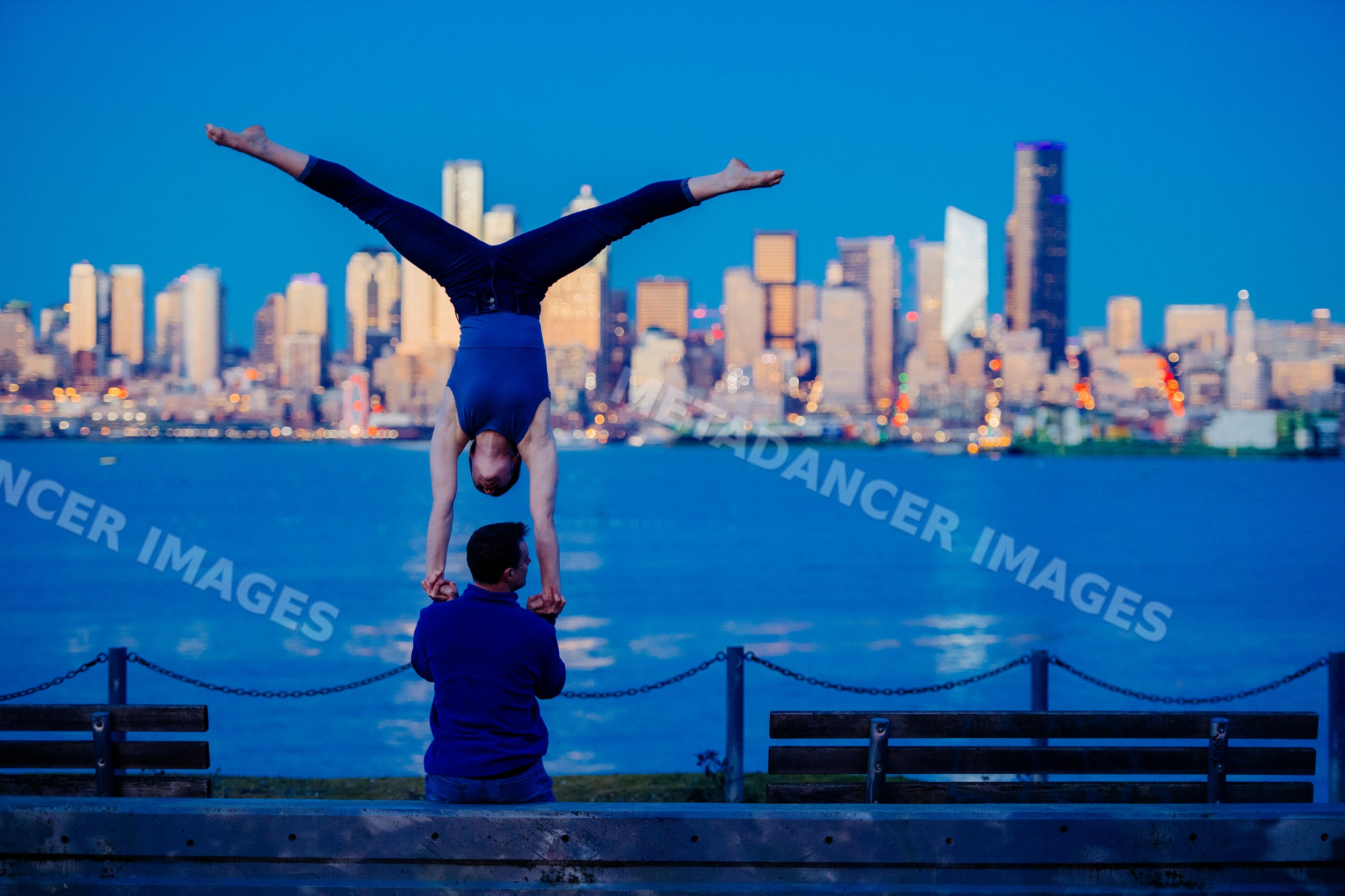 Partner acrobatics handstand by Seattle waterfront at evening