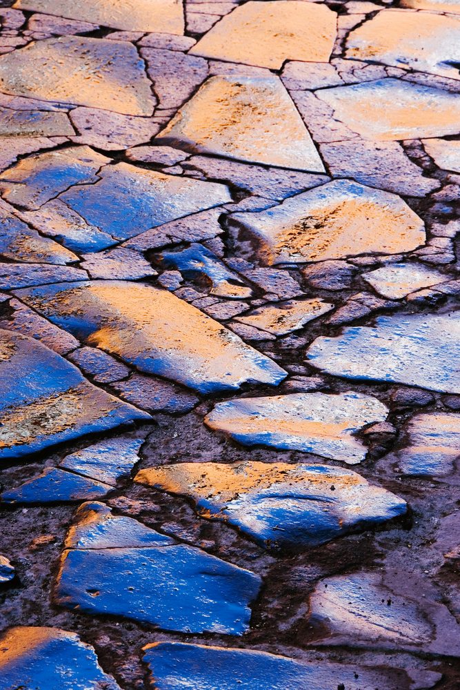 Damp cobblestones reflecting blue and orange light on outdoor pathway