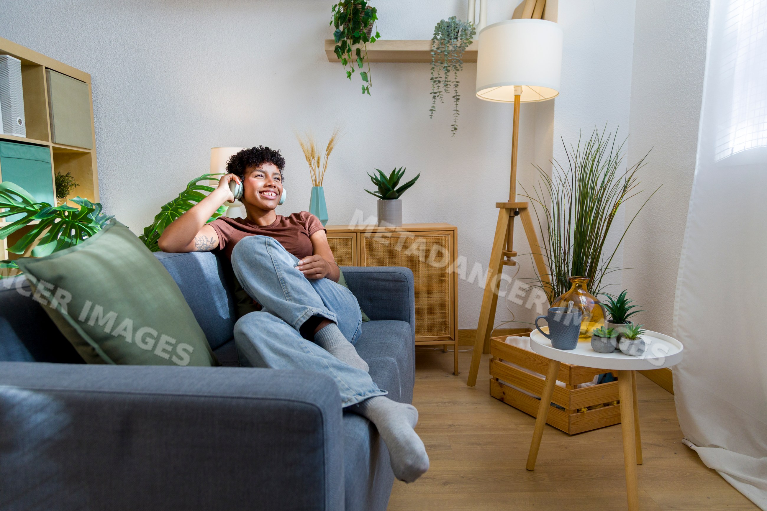 African American woman listening to music on sofa in home living room