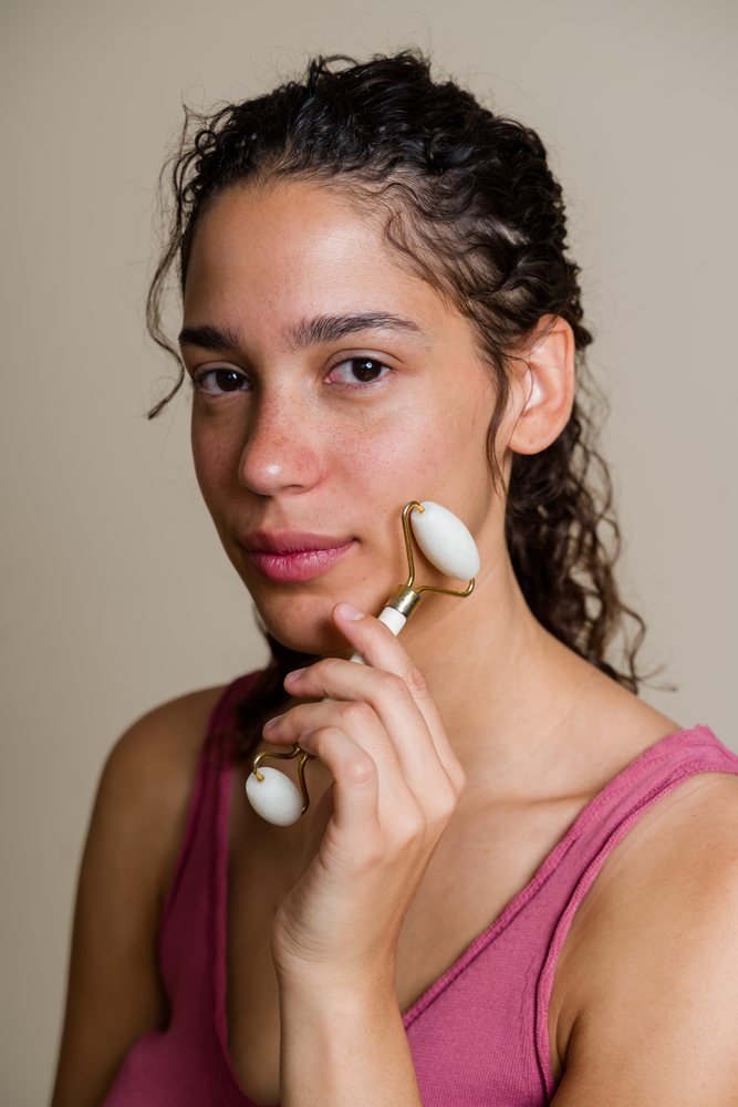 Hispanic woman massaging face with facial roller in spa setting