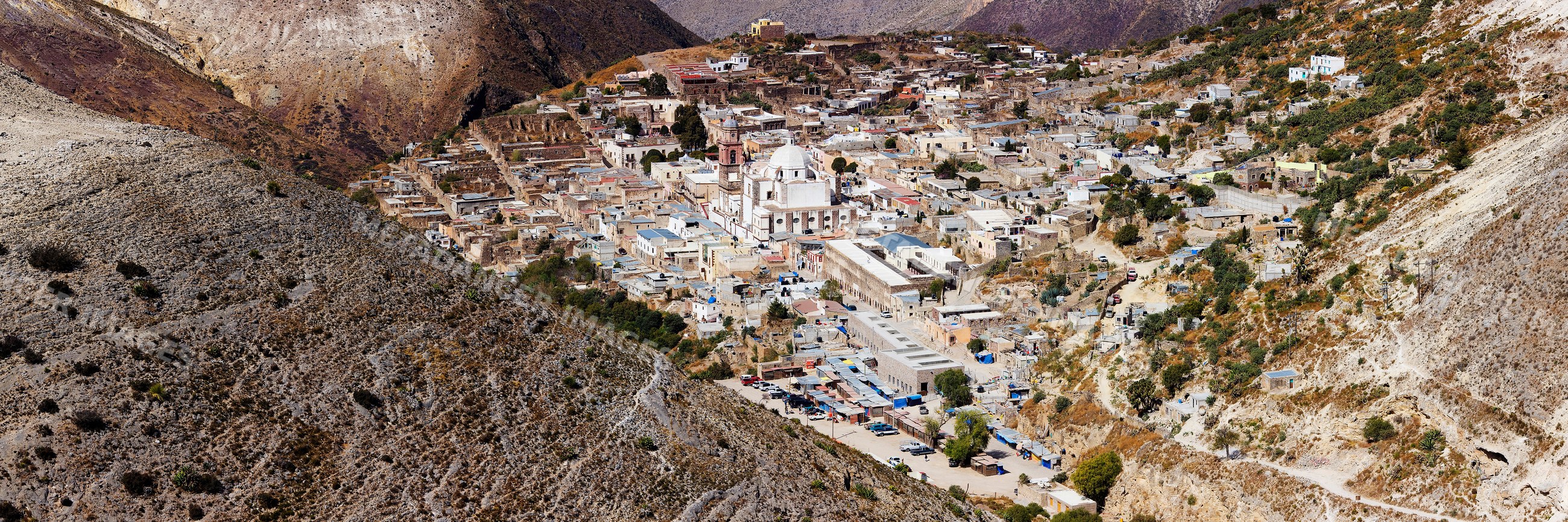 Panoramic aerial view of mountain town surrounded by barren hills