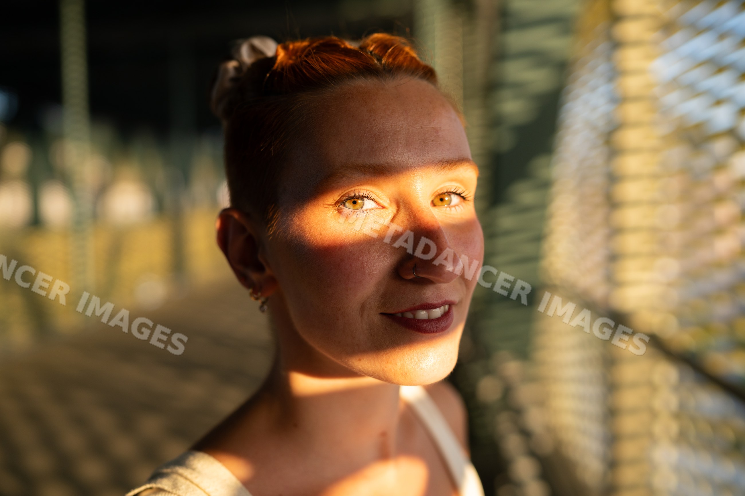 Young woman smiles with sunlight and shadow patterns on her face