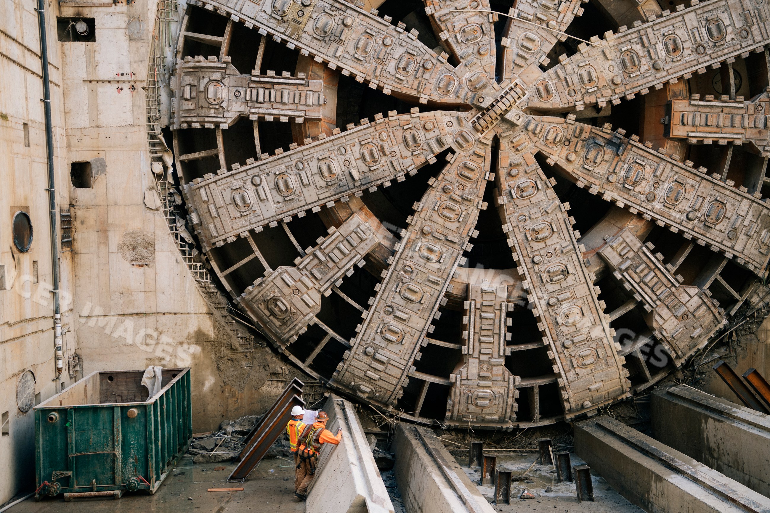 Two construction white workers inspect tunnel boring machine