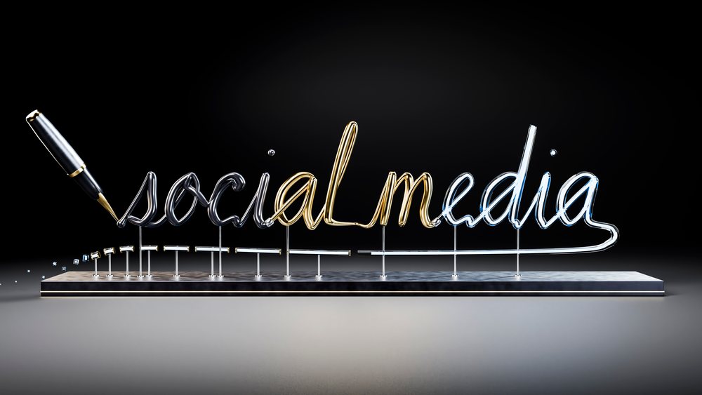 Metallic cursive writing of social media with pen on dark background