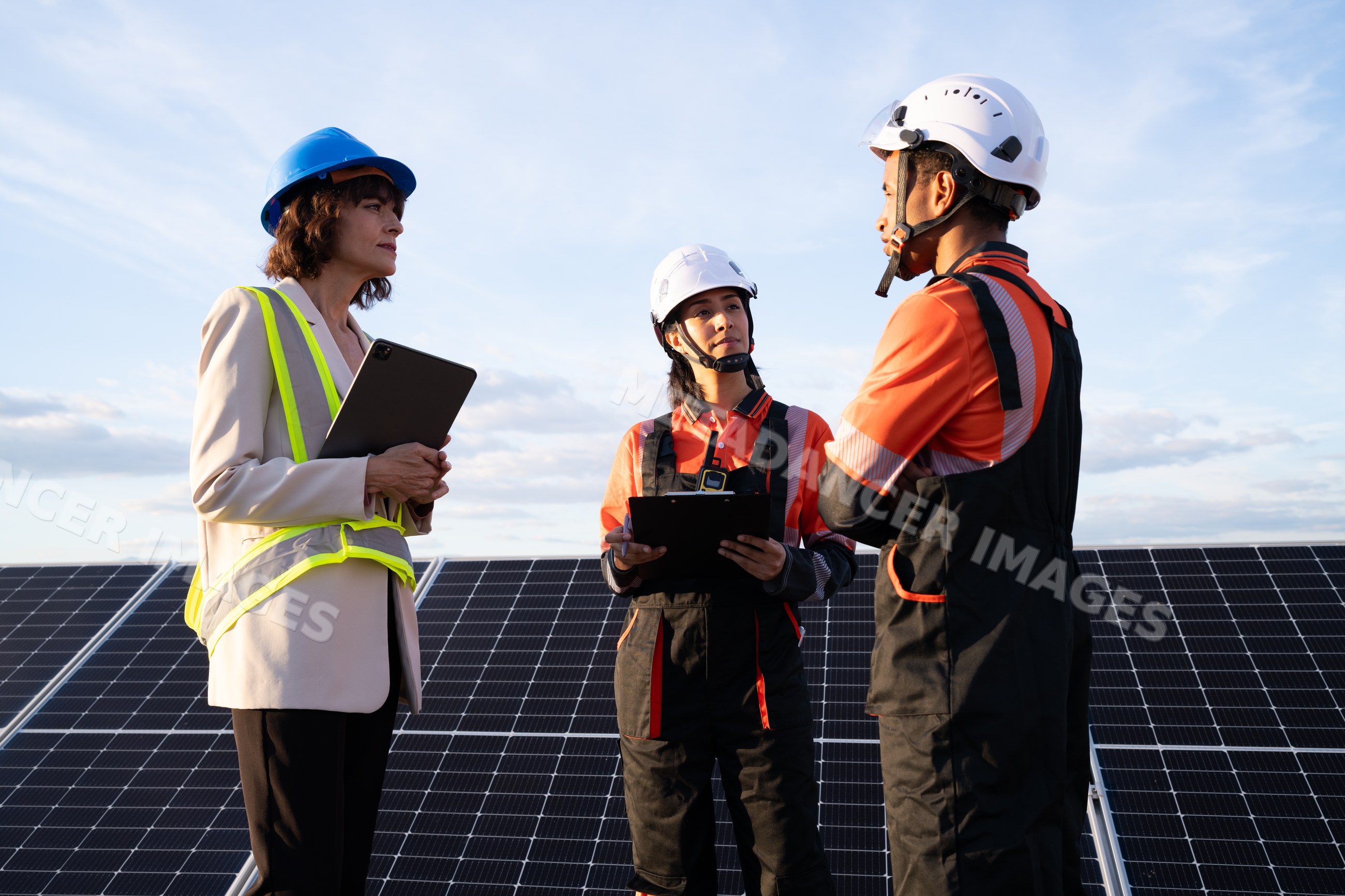 Engineers discussing solar energy project beside solar panels