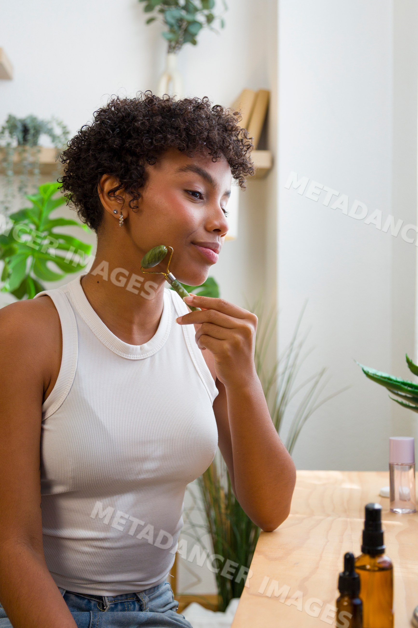African American woman massaging face with jade roller