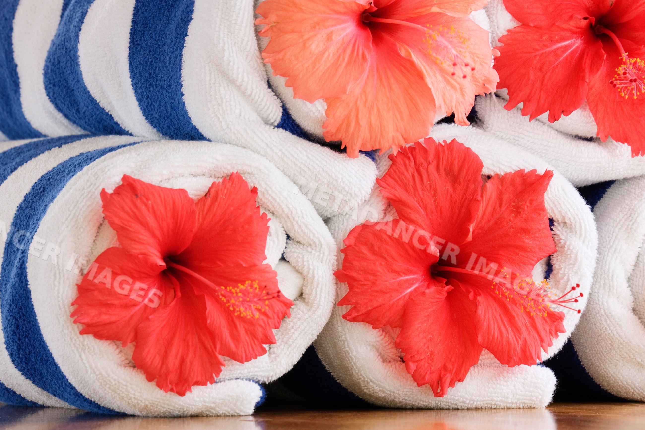 Rolled beach towels with red hibiscus flowers resort