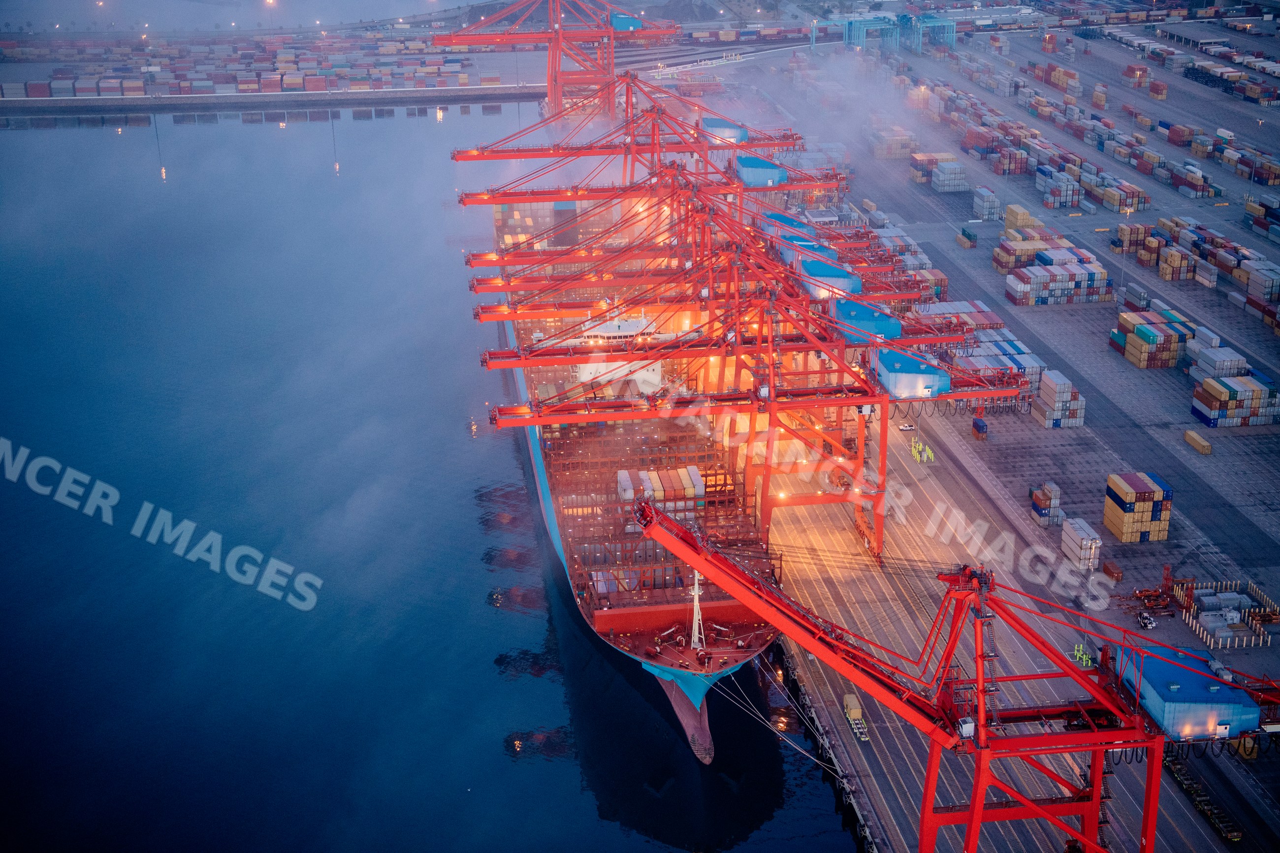 Container ship loaded by red cranes