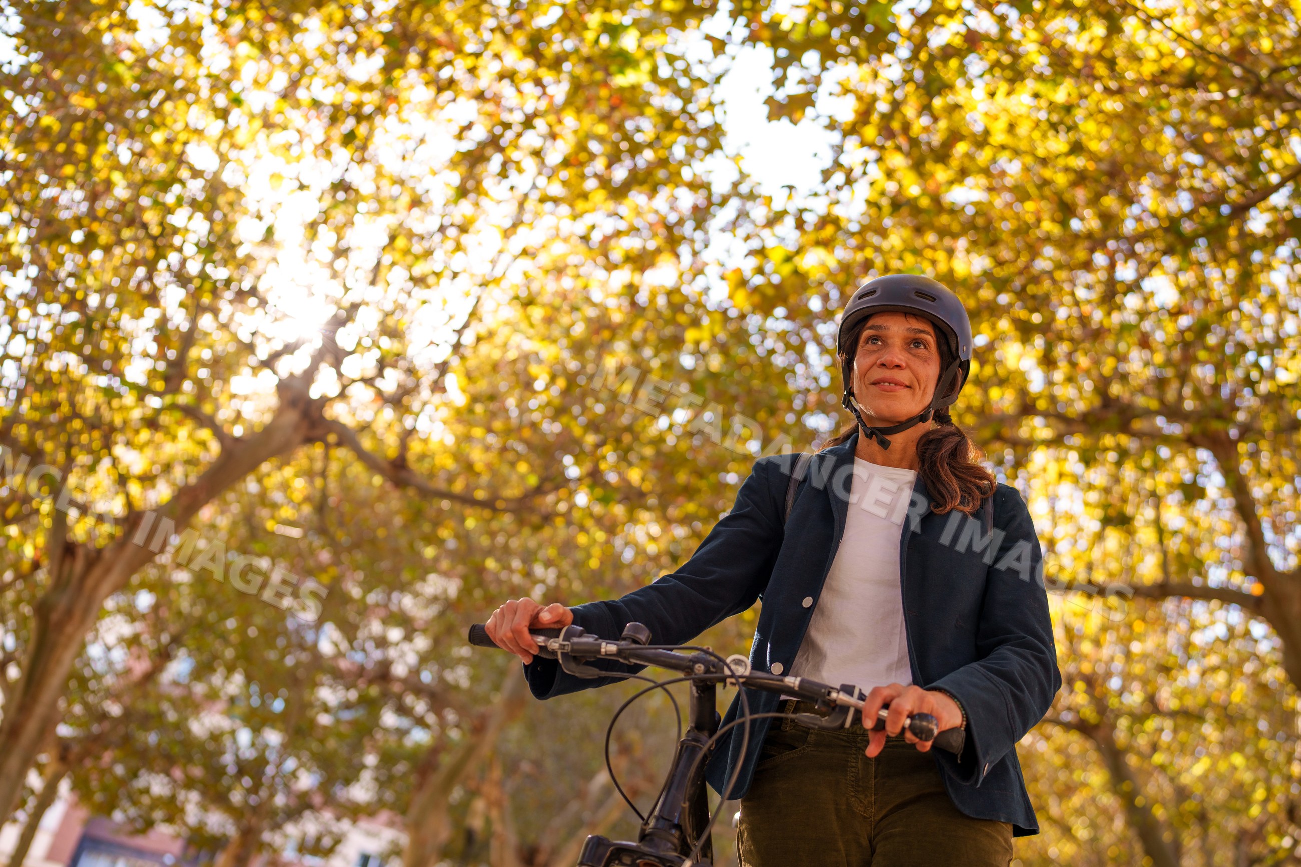 Hispanic woman riding bicycle outdoors under autumn trees